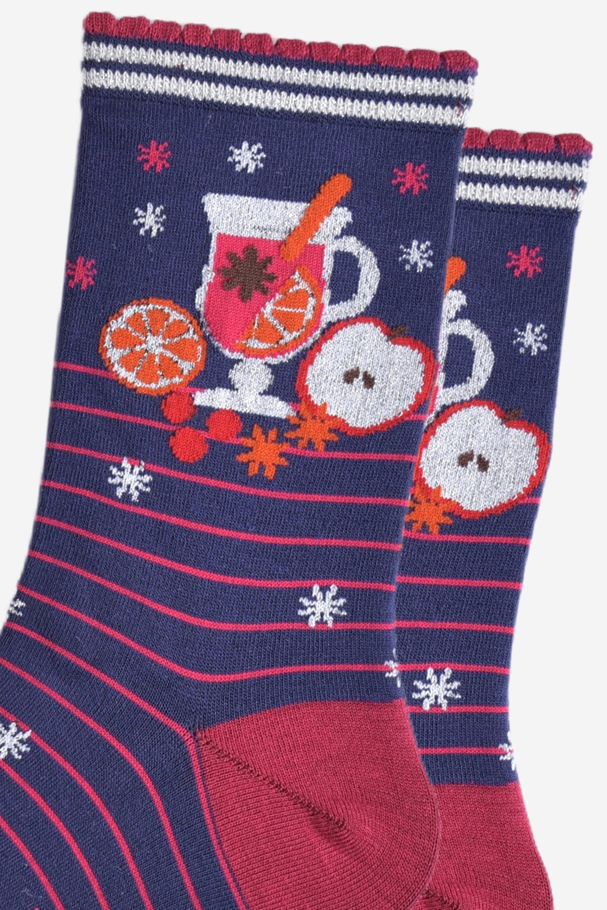 close up of the mulled wine carafe on the ankle of the socks, it is surrounded by orange and apple slices and star anise spice