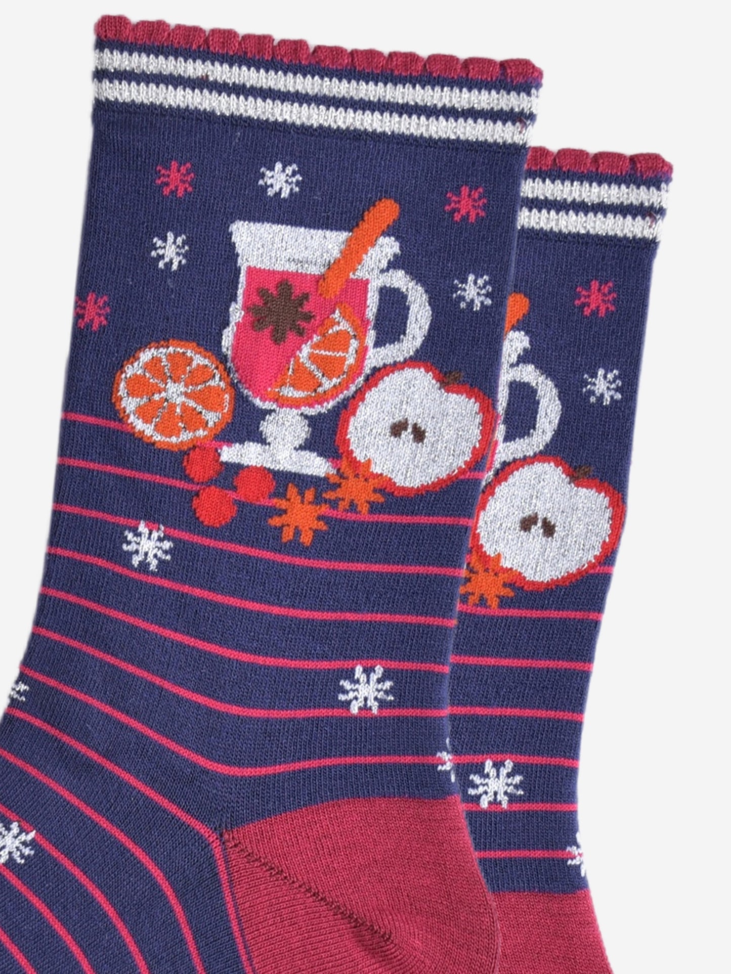 close up of the mulled wine carafe on the ankle of the socks, it is surrounded by orange and apple slices and star anise spice