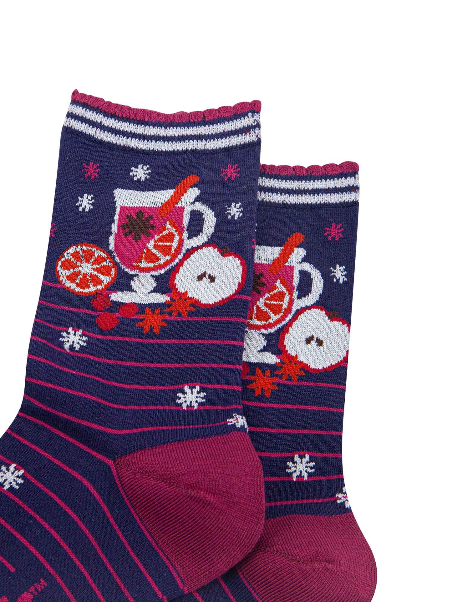close up of the mulled wine carafe on the ankle of the socks, it is surrounded by orange and apple slices and star anise spice