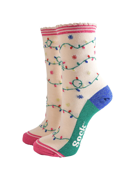 cream bamboo socks with an all over pattern of multicoloured party lights. the soles are green. the heel is blue and the socks have sparkly glitter accents