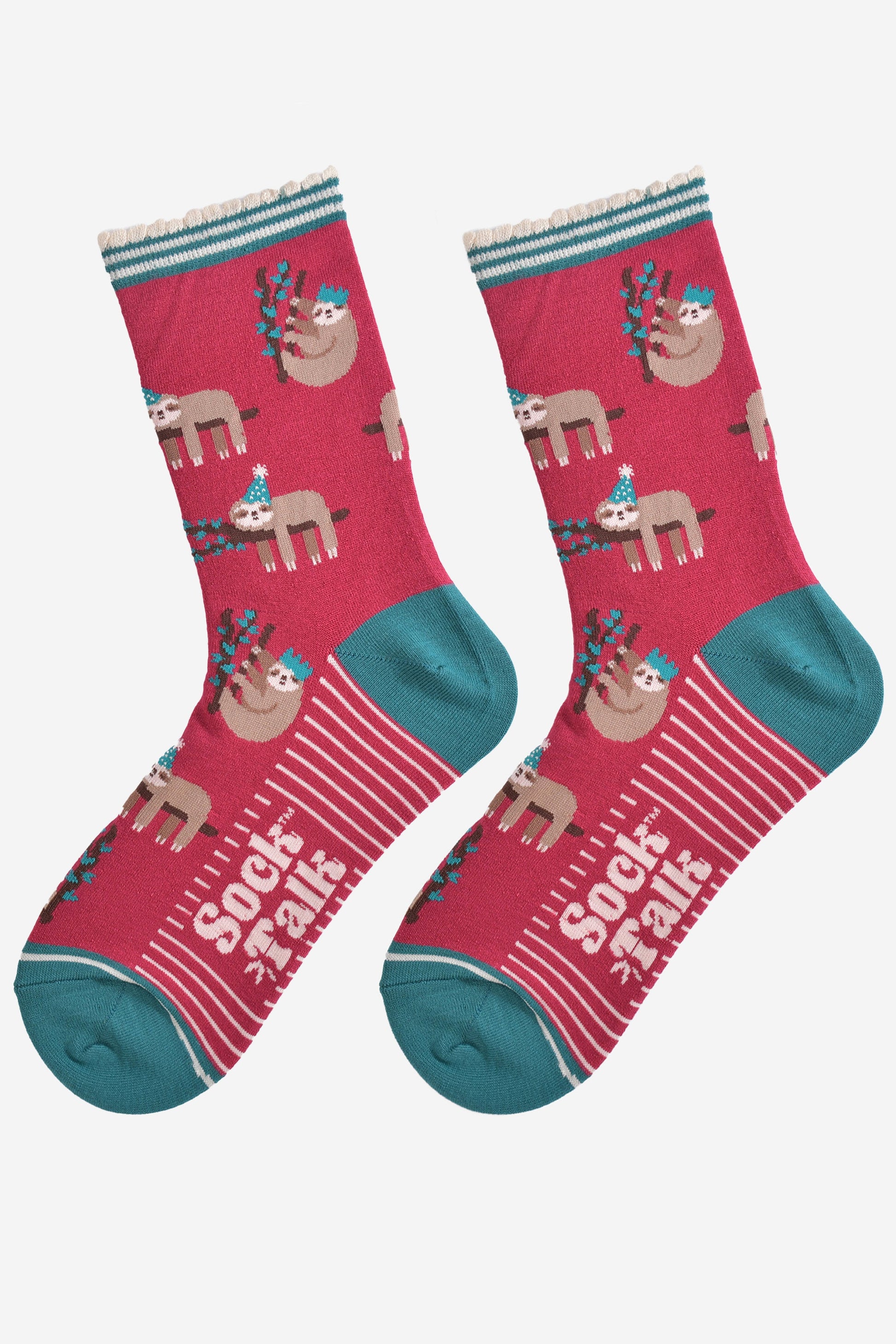 showing the festive sloth socks laying flat displaying the full pattern, there are sloths laying and climbing on tree branches while wearing green party hats, the sole of the socks have a white striped pattern