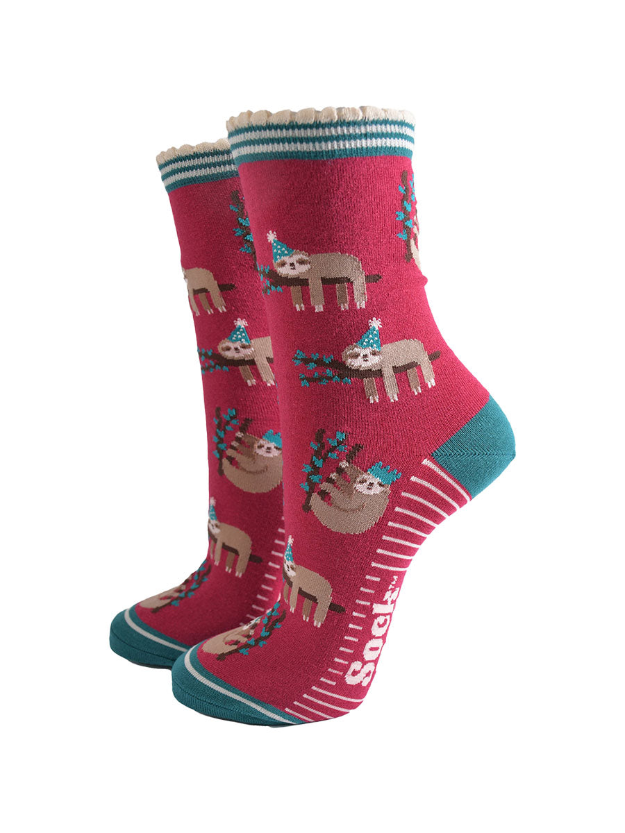berry red socks with a green heel, toe and striped cuff with a pattern of sleepy sloths wearing xmas hats