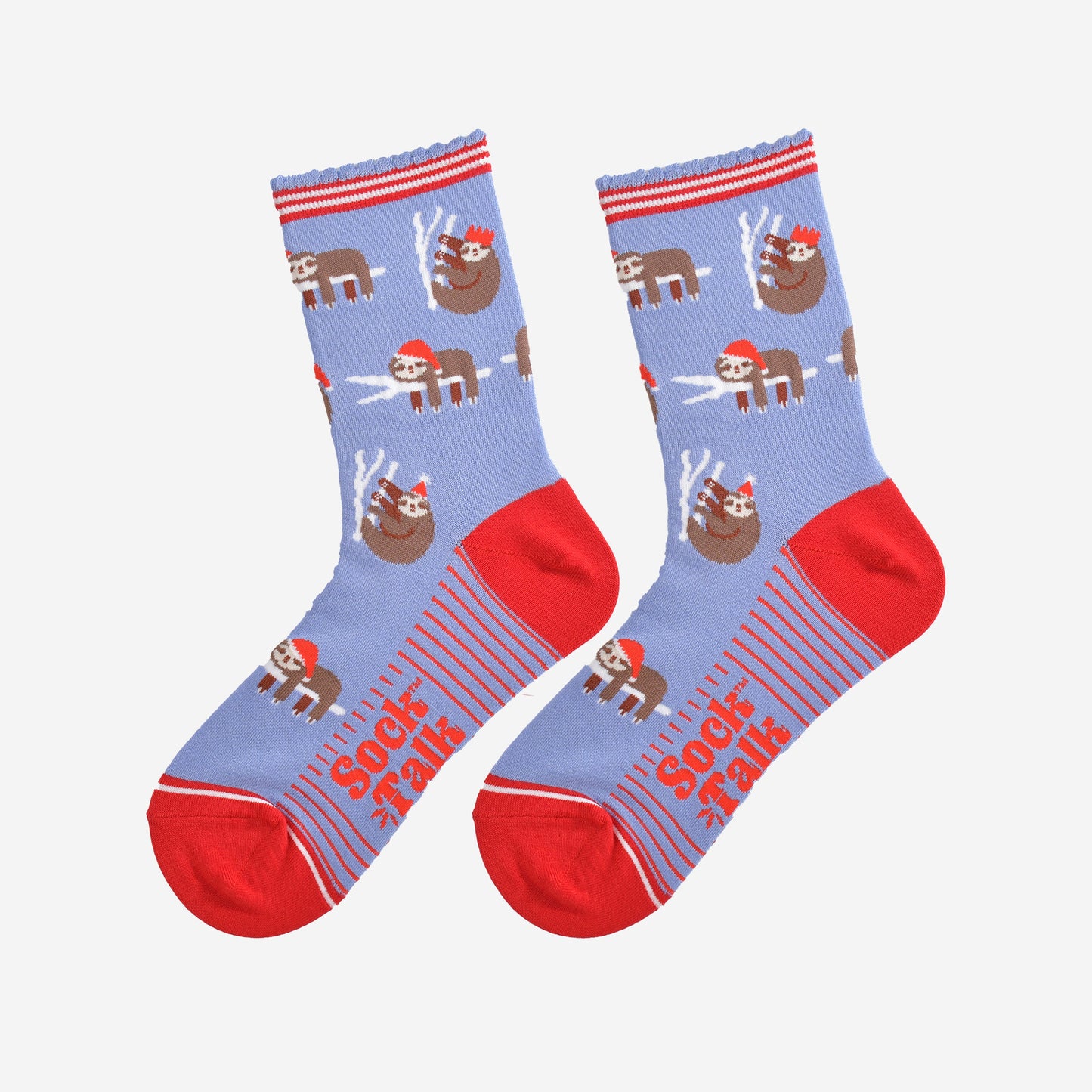 showing the festive sloth socks laying flat displaying the full pattern, there are sloths laying and climbing on tree branches while wearing santa hats and party hats, the sole of the socs have a red striped pattern