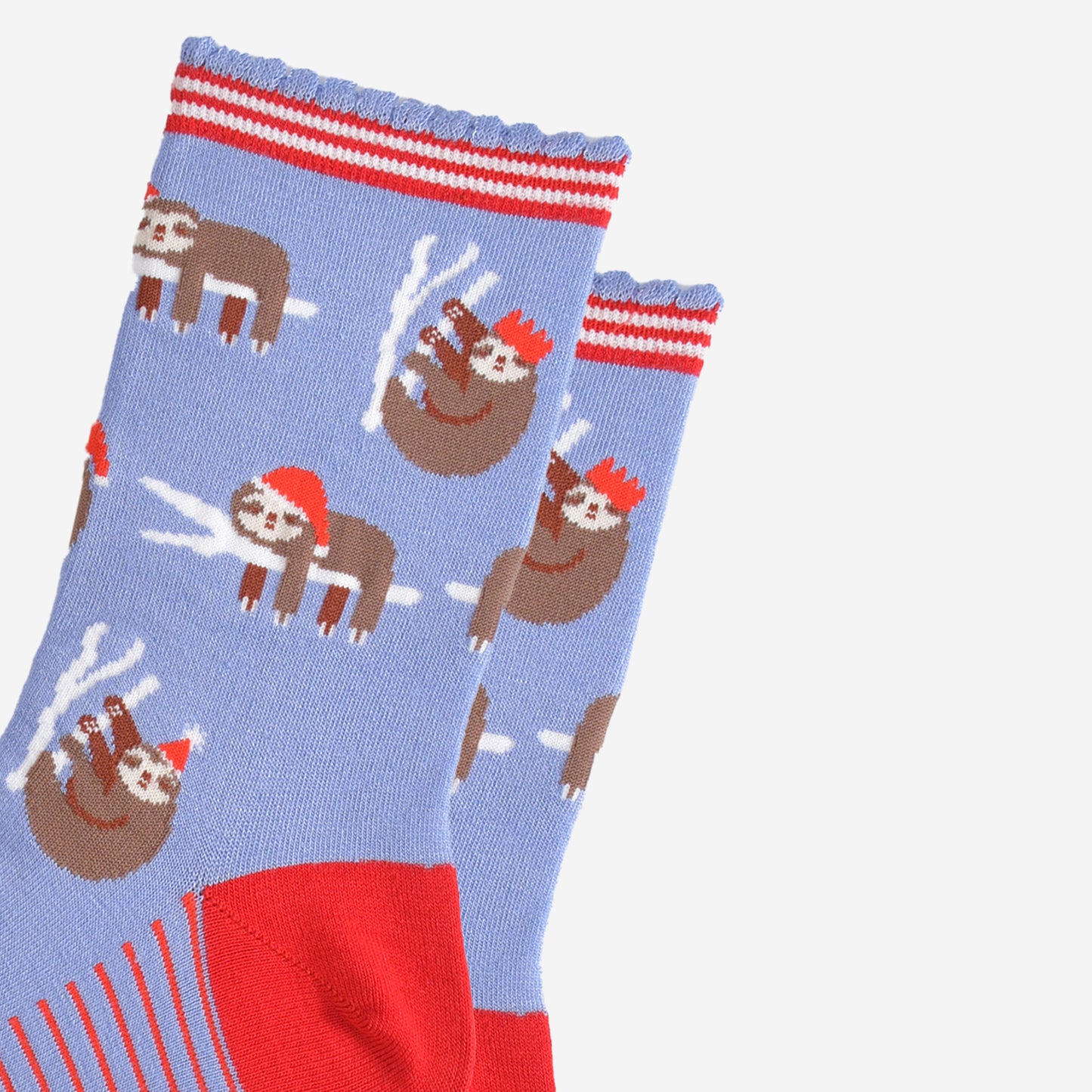 close up of the sloth pattern on the socks, there are sloths laying flat on a branch with their limbs dangling, these are wearing santa hats, there also sloths climbing branches, these are wearing festive party hats