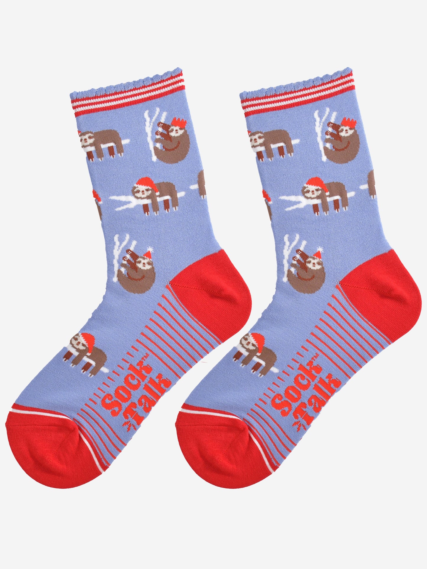 showing the festive sloth socks laying flat displaying the full pattern, there are sloths laying and climbing on tree branches while wearing santa hats and party hats, the sole of the socs have a red striped pattern