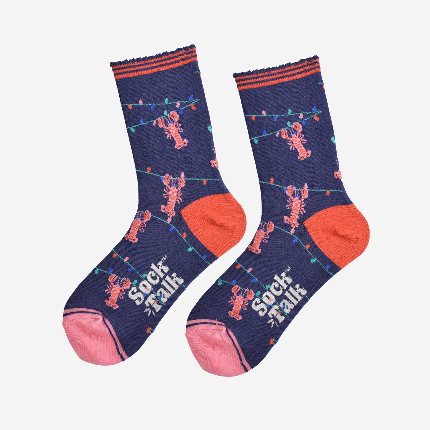 showing the lobster socks laying flat highlighting the all over pattern of the colourful party lights with pink lobsters hanging from them, the toe is pink and the heel is coral in contrast to the navy blue of the socks