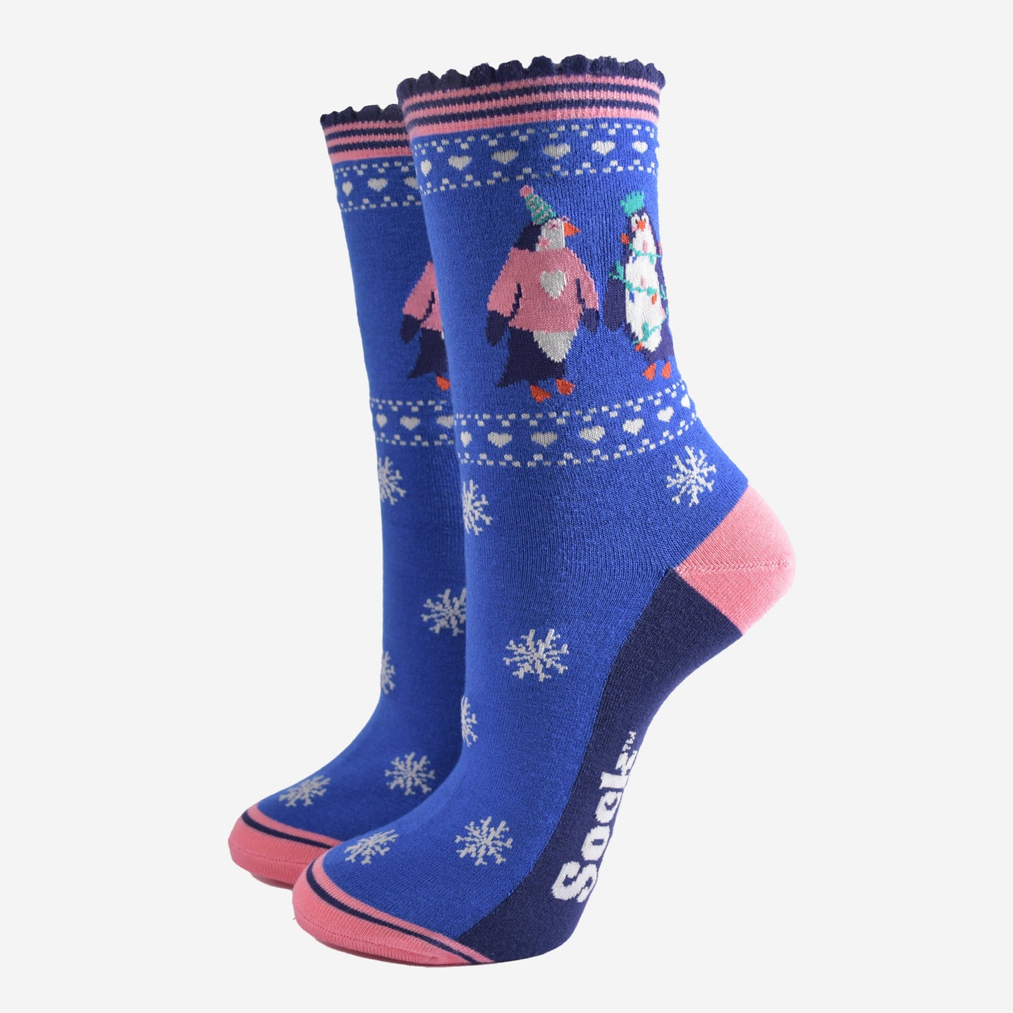 blue socks with pink accents and white snow flakes with a penguins on the ankle, the penguins are wearing party hats, xmas jumpers and christmas party lights