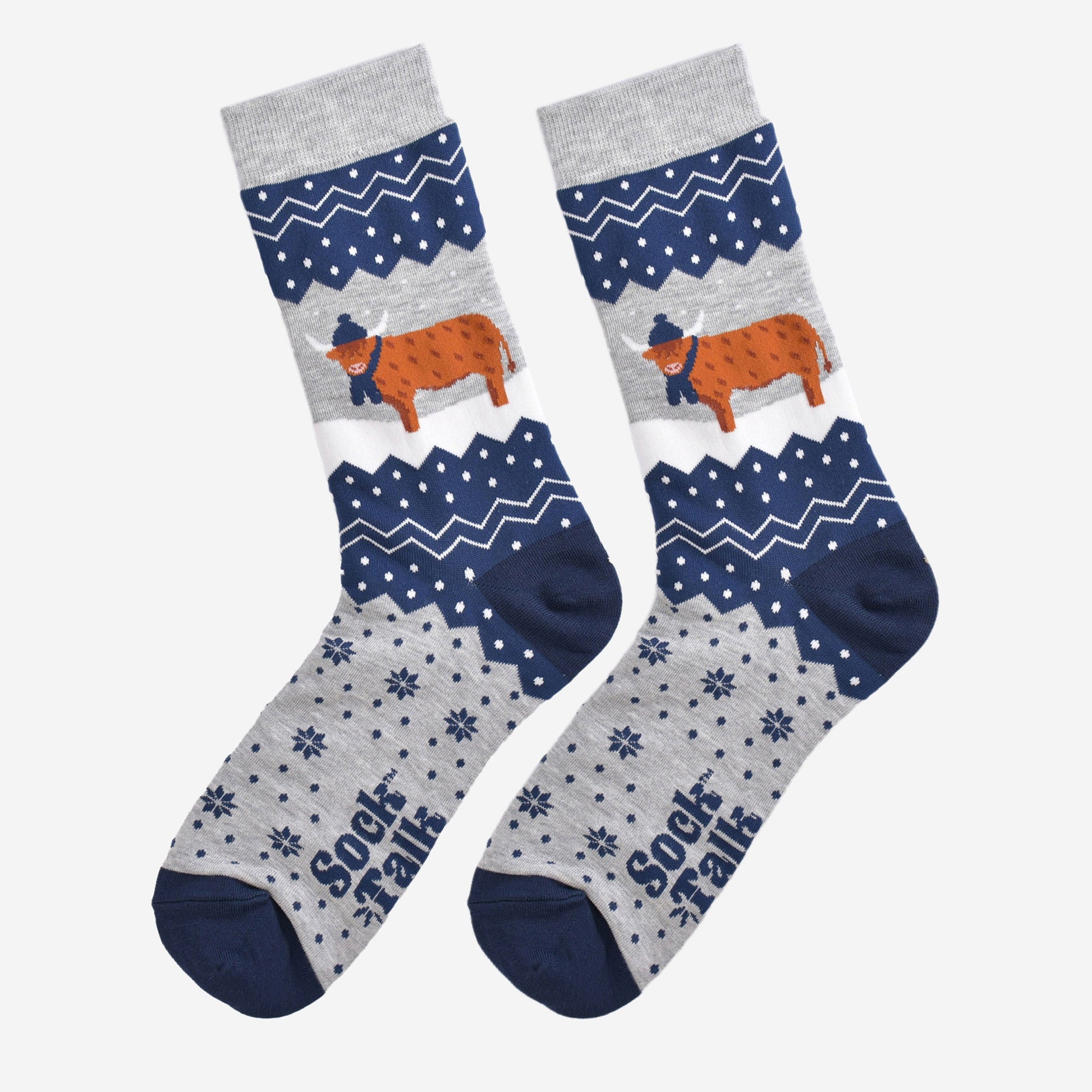 showing these grey and blue fair isle pattern highland cow socks laying flat, showing the overall festive winter pattern