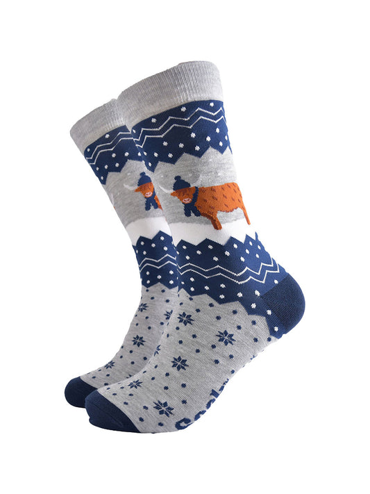 navy blue and grey bamboo socks with a fair isle zig zag and snowflake pattern, featuring a highland cow standing in a snowy field wearing a blue winter hat