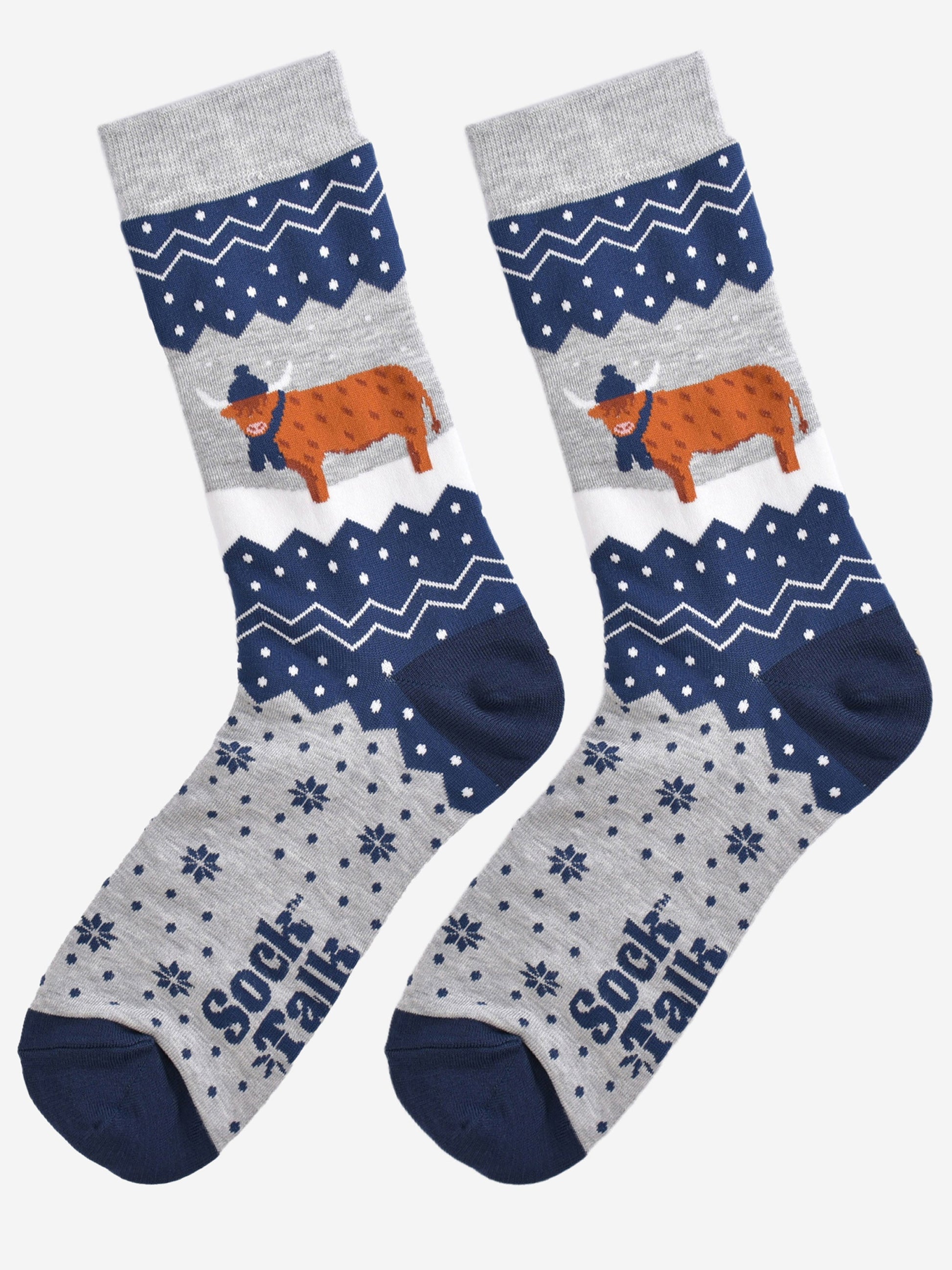 showing these grey and blue fair isle pattern highland cow socks laying flat, showing the overall festive winter pattern