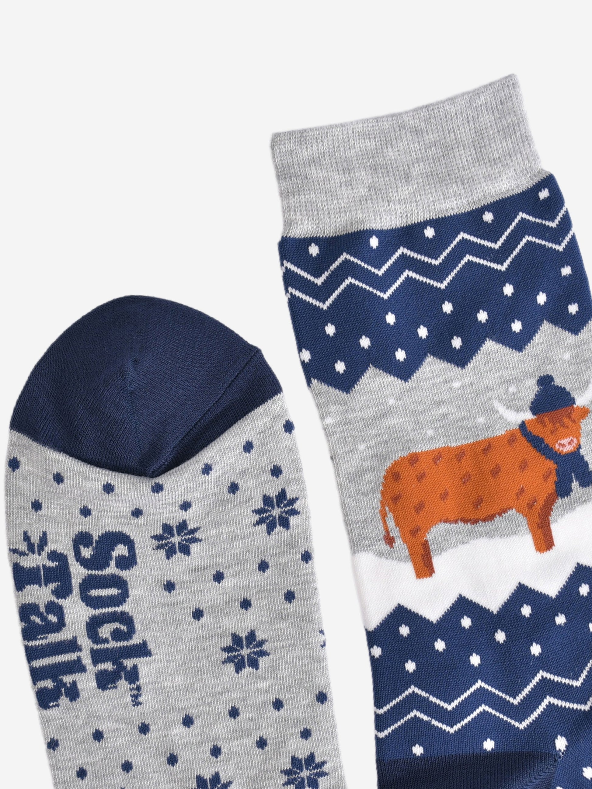 showing the toe and cuff of the socks, showing clearly the fair isle pattern and highland cow, the cow is wearing a winter hat and scarf