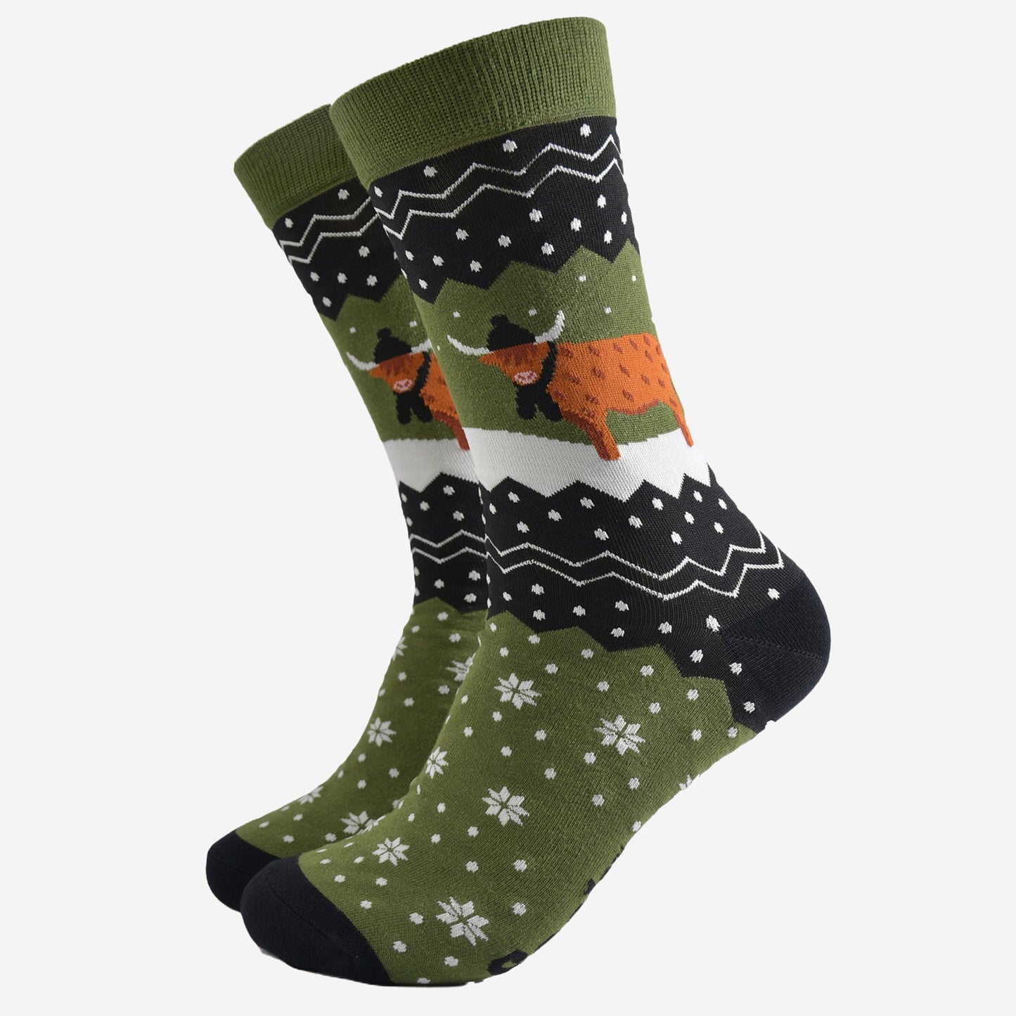 green and black bamboo socks with a fair isle zig zag and snowflake pattern, featuring a highland cow standing in a snowy field wearing a black winter hat