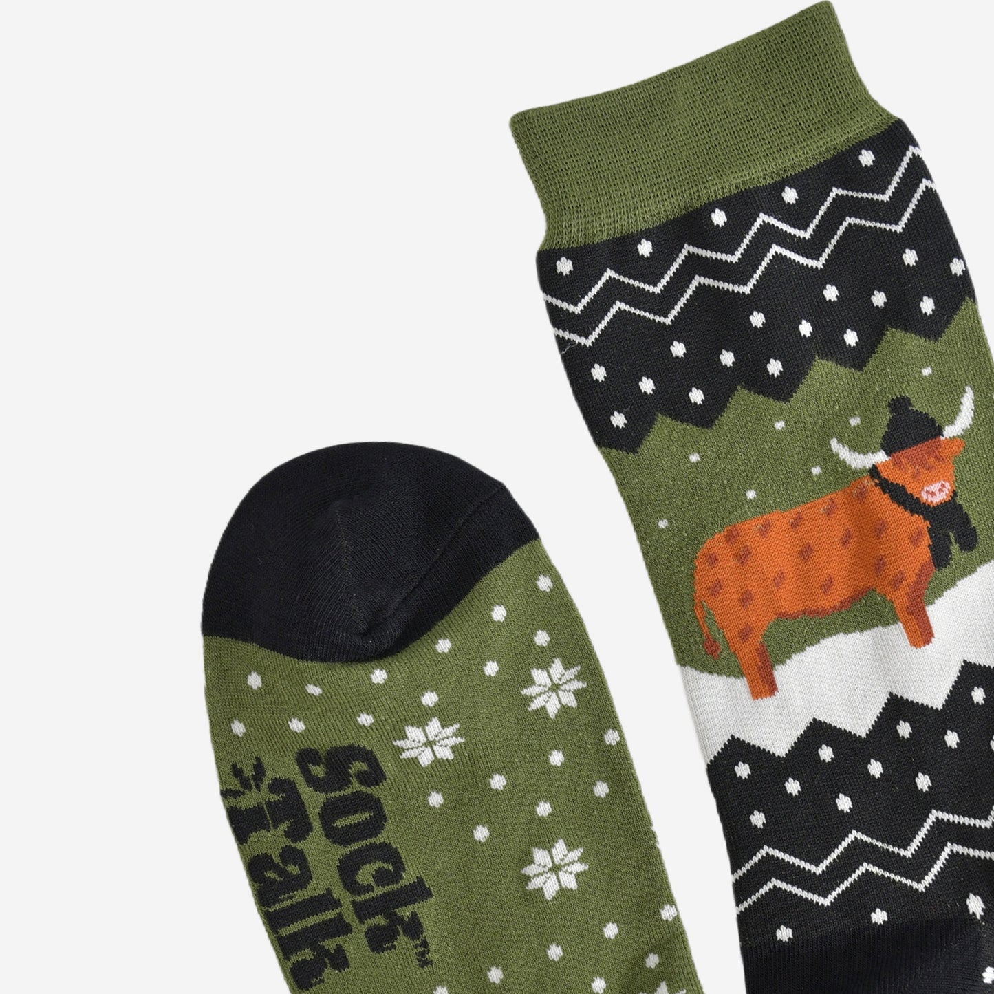 showing the toe and cuff of the socks, showing clearly the fair isle pattern and highland cow, the cow is wearing a winter hat and scarf