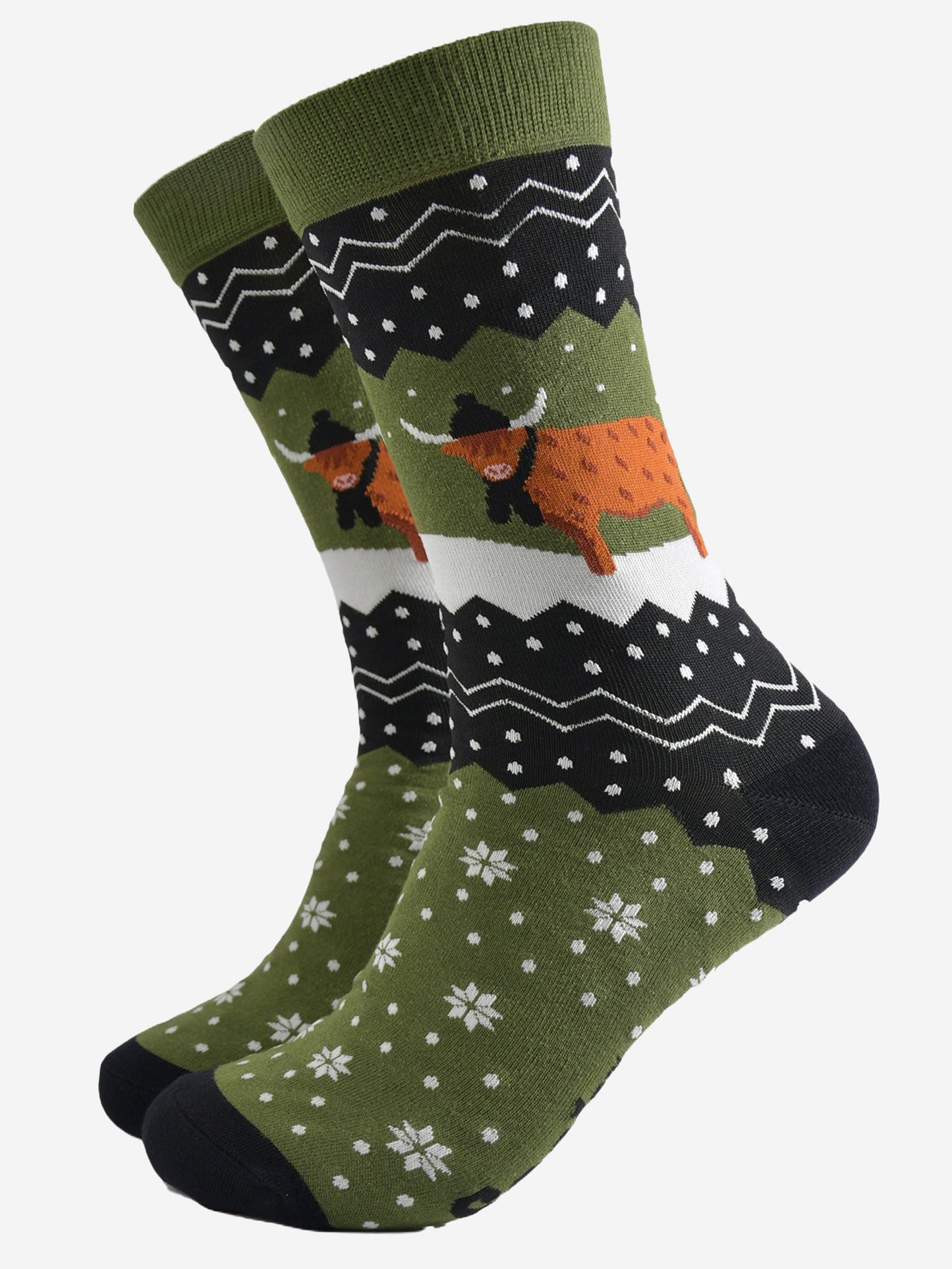 green and black bamboo socks with a fair isle zig zag and snowflake pattern, featuring a highland cow standing in a snowy field wearing a black winter hat