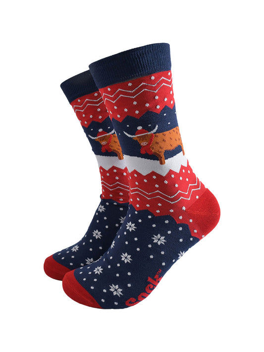 navy blue and red bamboo socks with a fair isle zig zag and snowflake pattern, featuring a highland cow standing in a snowy field wearing a santa hat