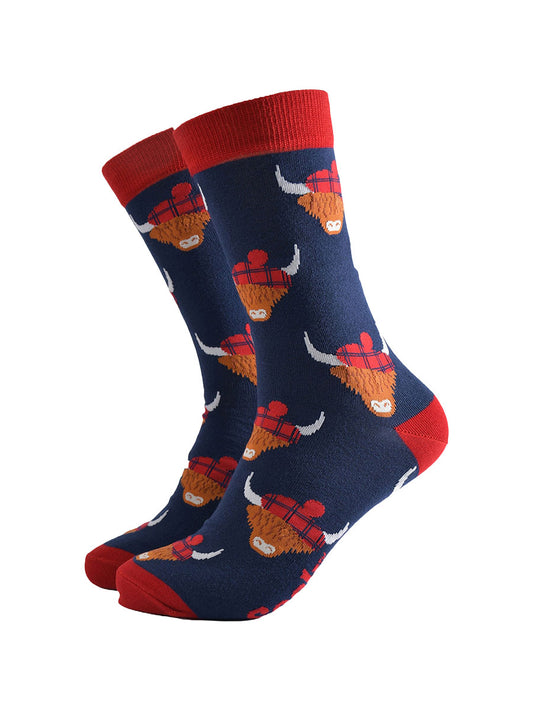 navy blue socks with red heel, toe and cuff with an all over pattern of highland cows wearing tartan pom pom hats
