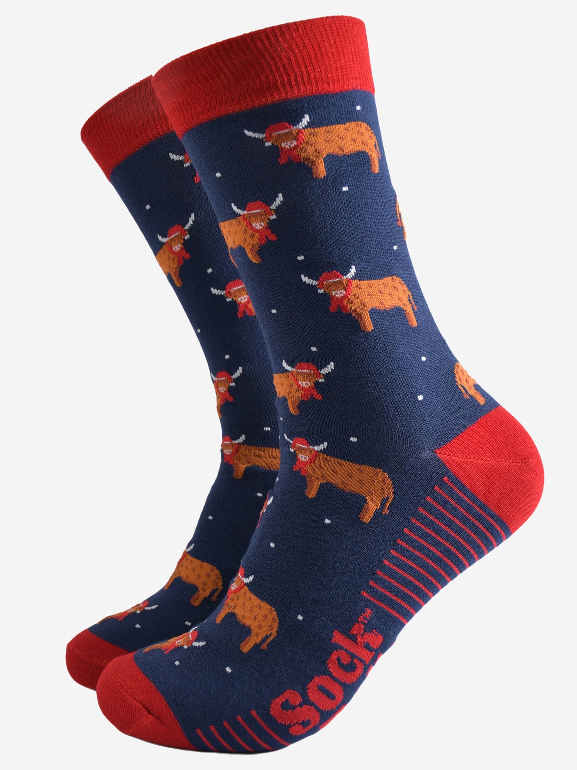 navy blue socks with a red heel, toe and trim with an all over pattern of highland cows wearing santa hats and winter scarves