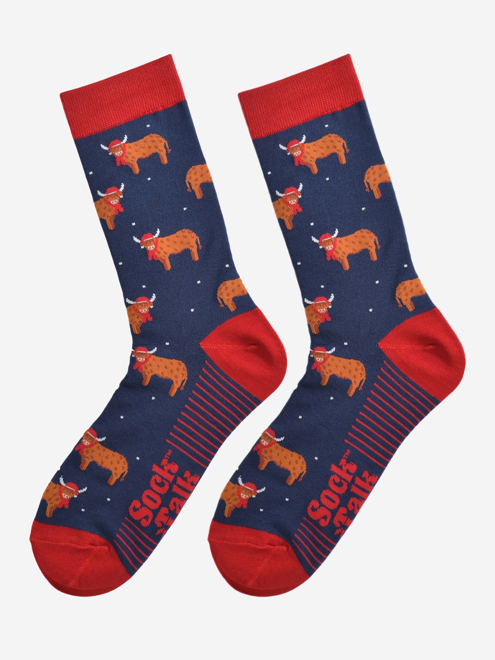 navy blue and red highland cow bamboo socks laying flat, the highland cows are shown in profile and they are standing up, they are wearing red santa hats and red winter scarves