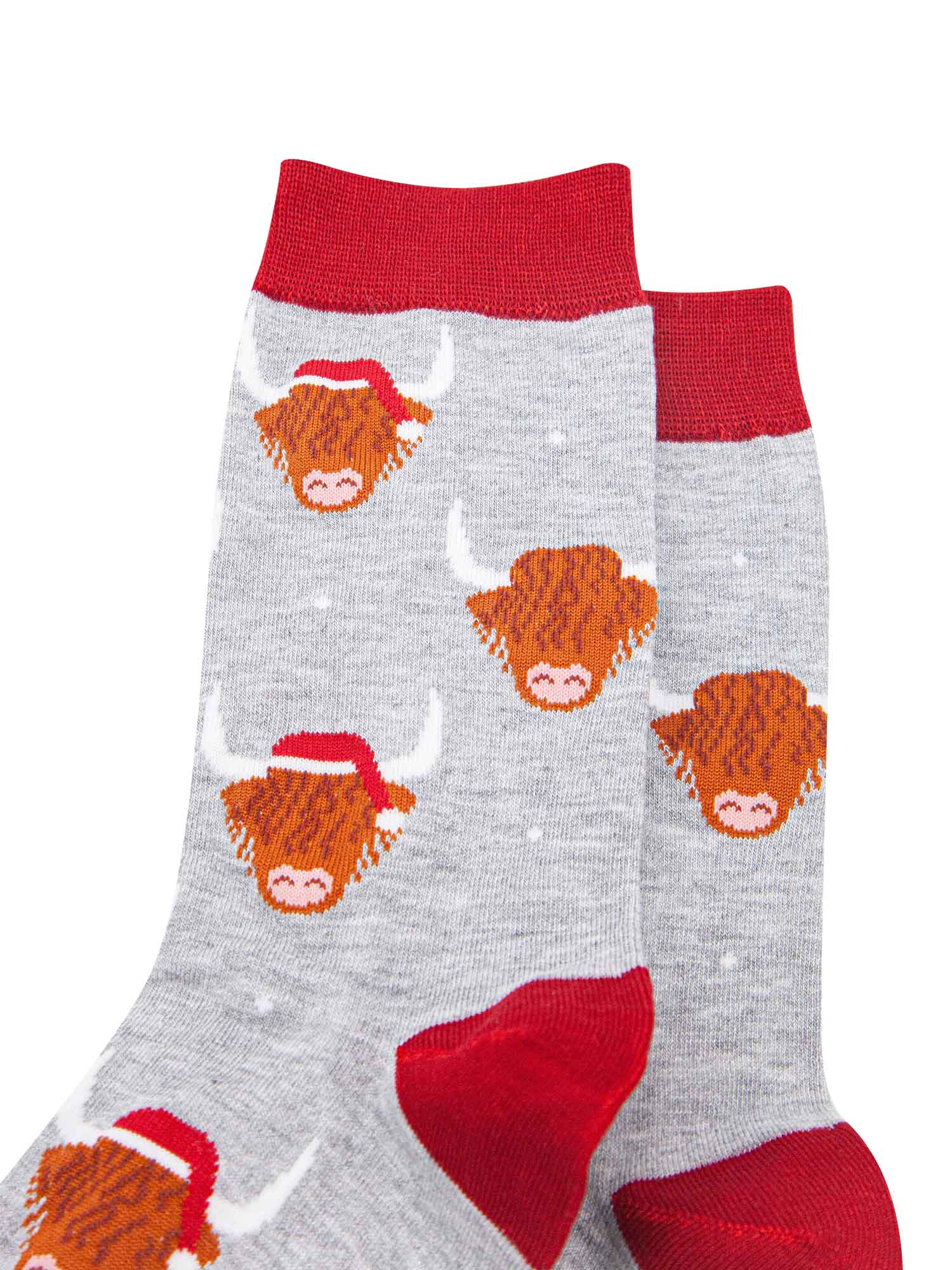 close up of the socks, showing the highland cow pattern where some of the cows are wearing santa hats, there is also a subtle white snowflake pattern on the socks