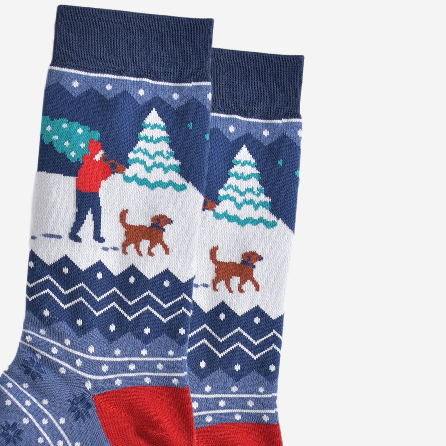 close up of the man and his dog design on the ankle, the man is carrying a christmas tree while walking through the snow with a brown dog