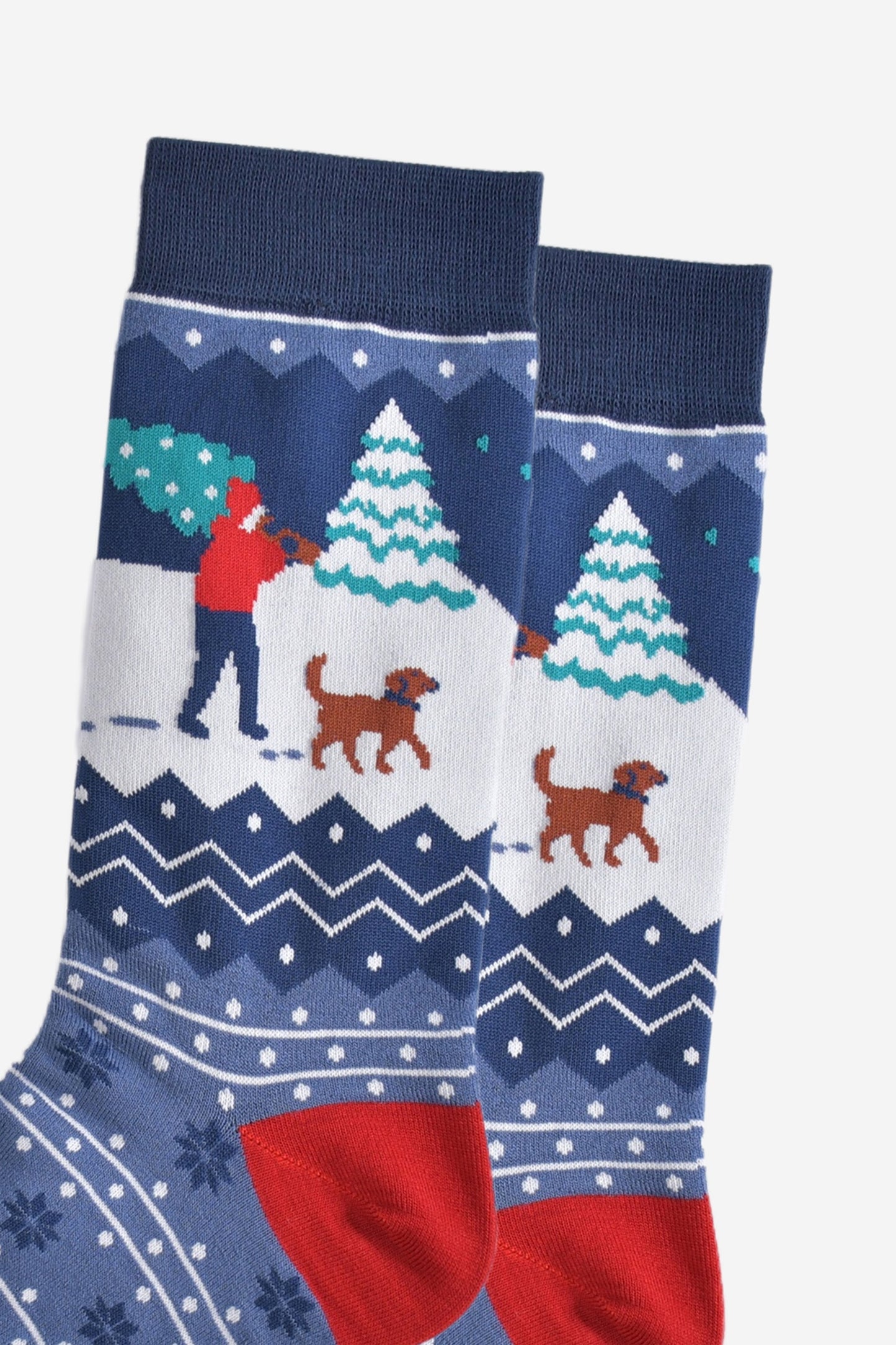 close up of the man and his dog design on the ankle, the man is carrying a christmas tree while walking through the snow with a brown dog