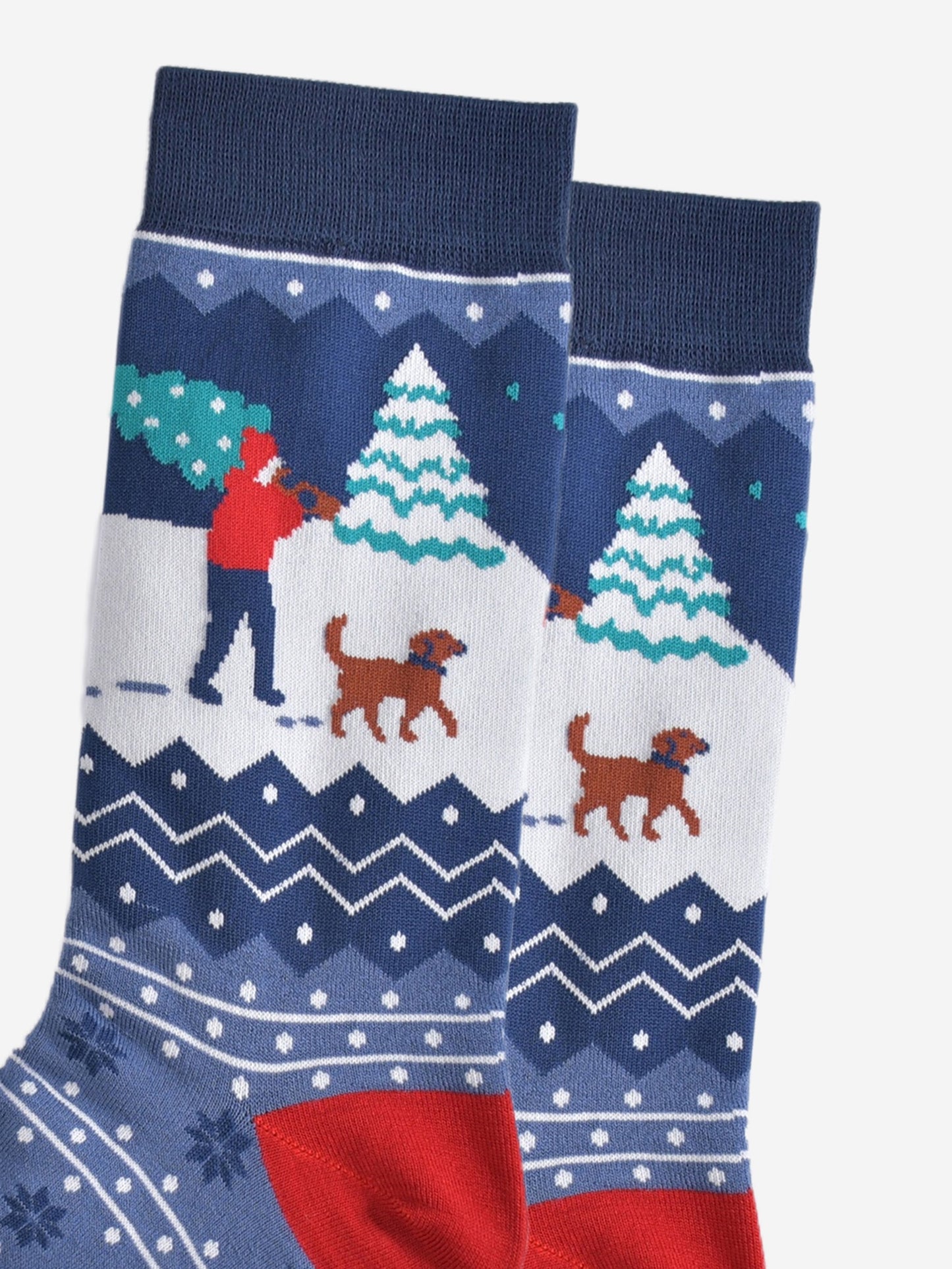 close up of the man and his dog design on the ankle, the man is carrying a christmas tree while walking through the snow with a brown dog