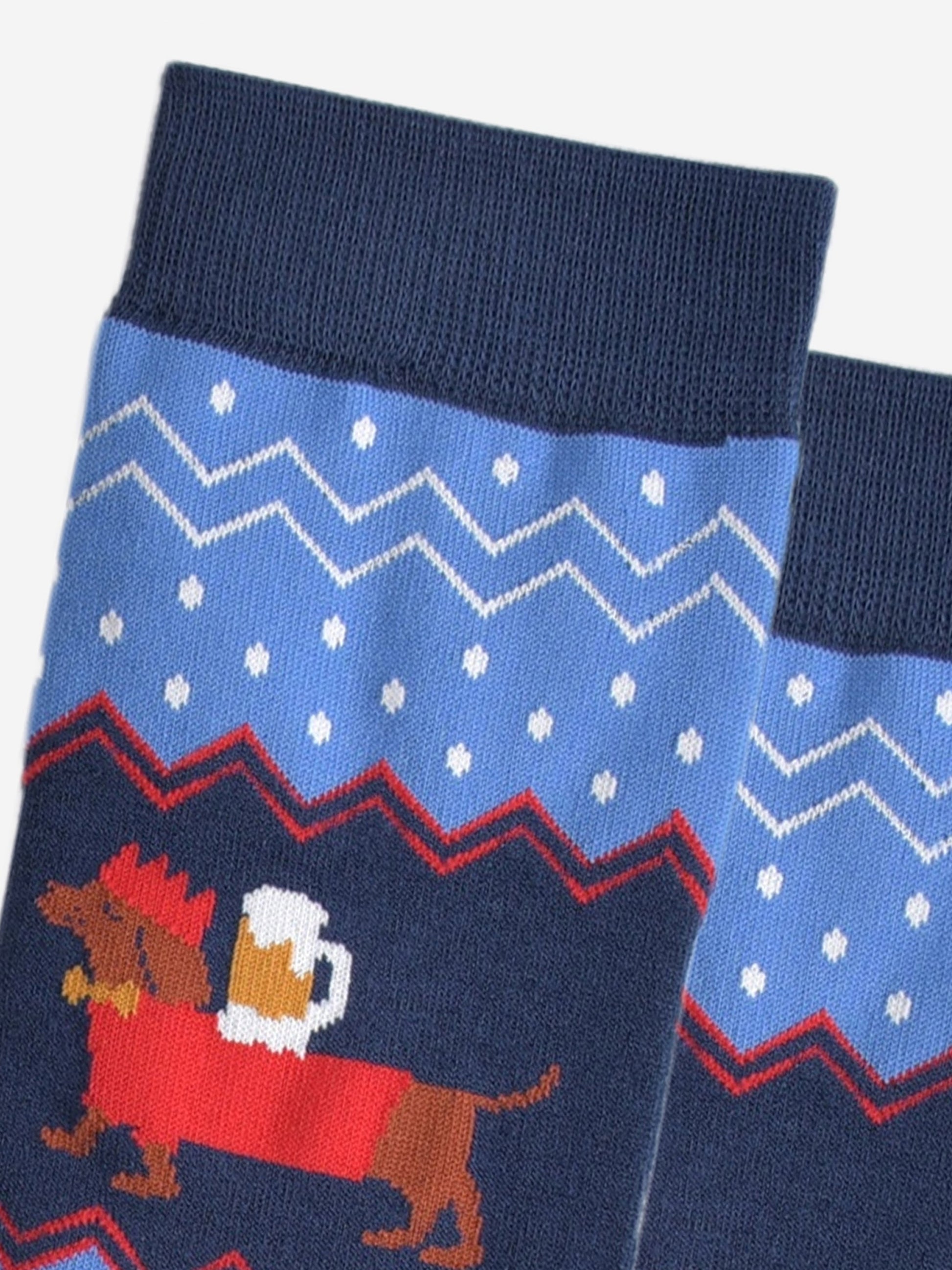 close up of the sausage dog, showing clearly that it is balancing a full pint of beer on its back, the dog is also wearing festive red jumper and red party hat