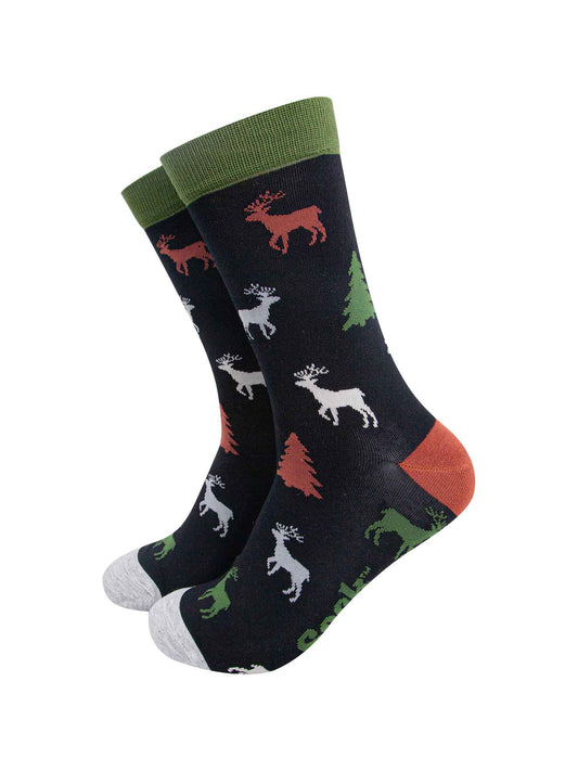 black crew socks with green cuff, grey toe and orange heel with a pattern of stags and christmas trees all over