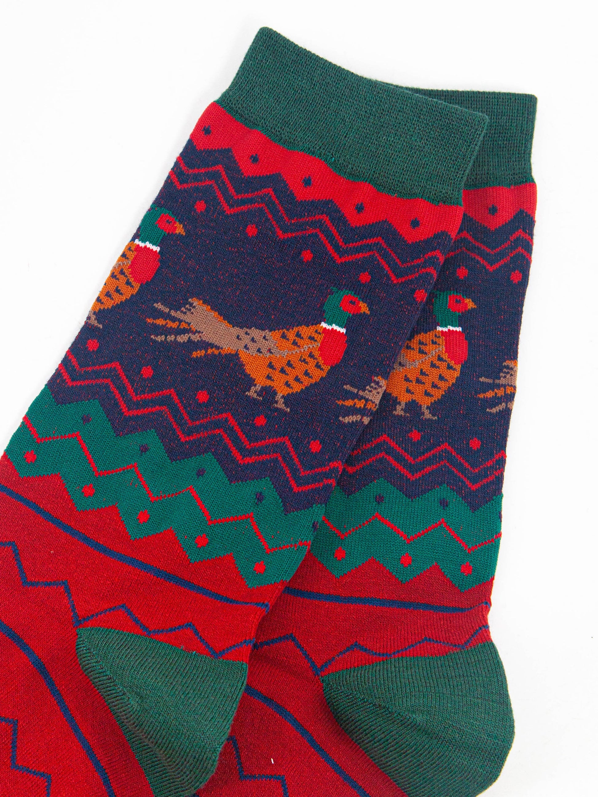 close up of the pheasant pattern on the ankle of the socks, the birds are brown and orange with red bellies and a green and red head. 