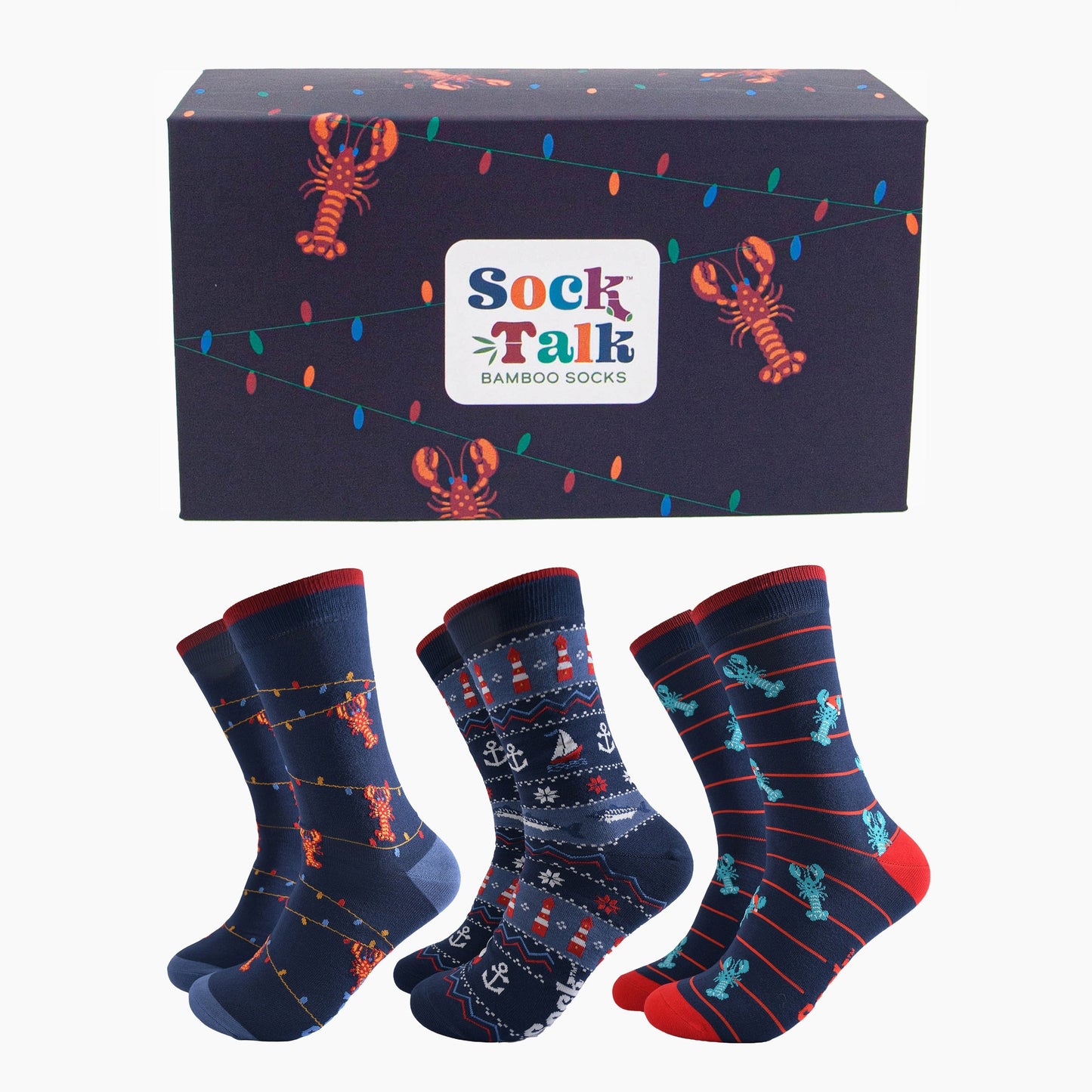 navy blue gift box with red lobsters dangling from colourful party lights, with three pairs of bamboo socks, blue lobsters wearing santa hats, fair isle nautical design featuring anchors, boats and lighthouses and one pair of red lobster socks showing them dangling from party lights