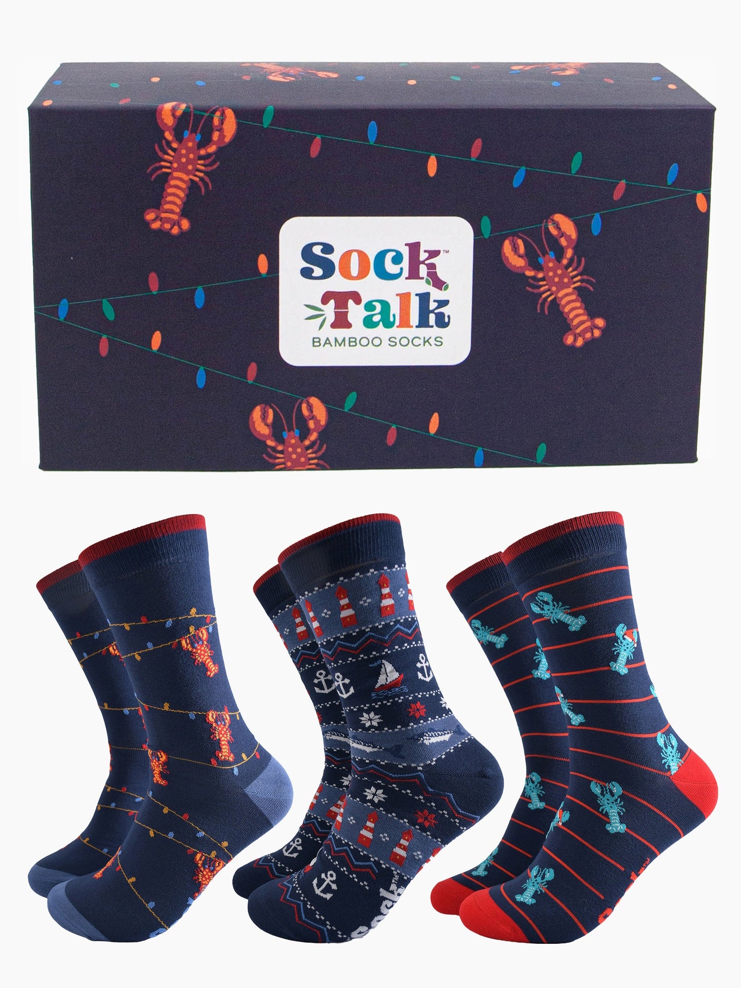 navy blue gift box with red lobsters dangling from colourful party lights, with three pairs of bamboo socks, blue lobsters wearing santa hats, fair isle nautical design featuring anchors, boats and lighthouses and one pair of red lobster socks showing them dangling from party lights