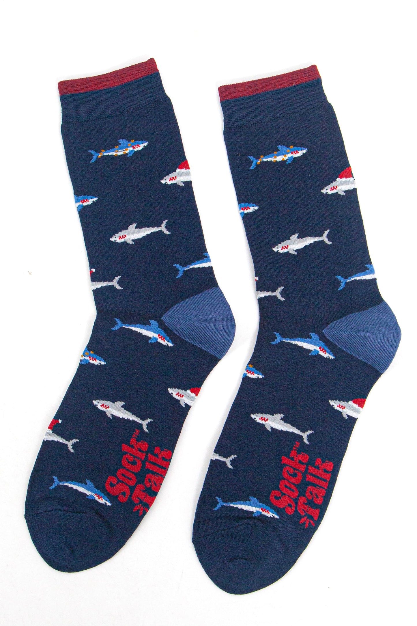 showing the shark socks laying flat, there is an all over pattern of swimming blue and grey sharks wearing festive hats and party lights