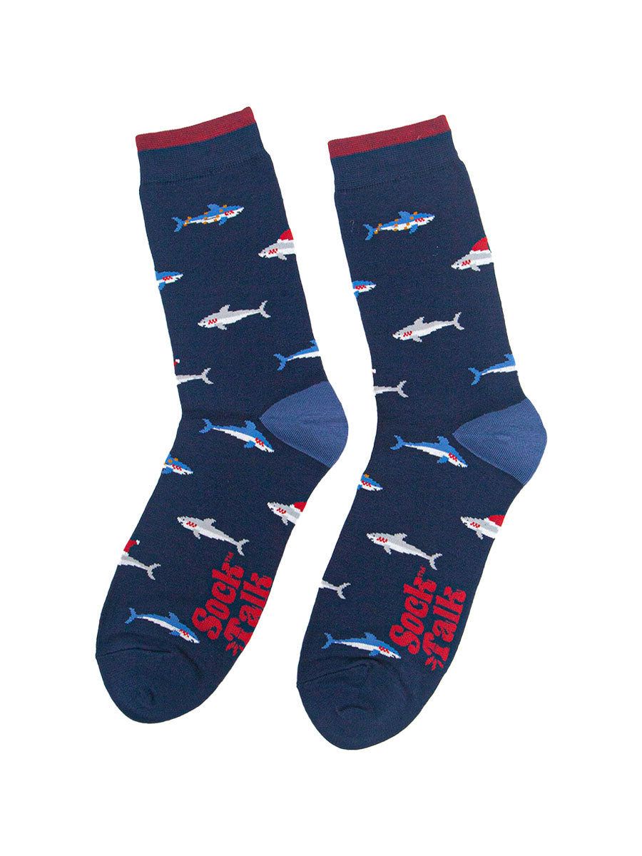 showing the shark socks laying flat, there is an all over pattern of swimming blue and grey sharks wearing festive hats and party lights