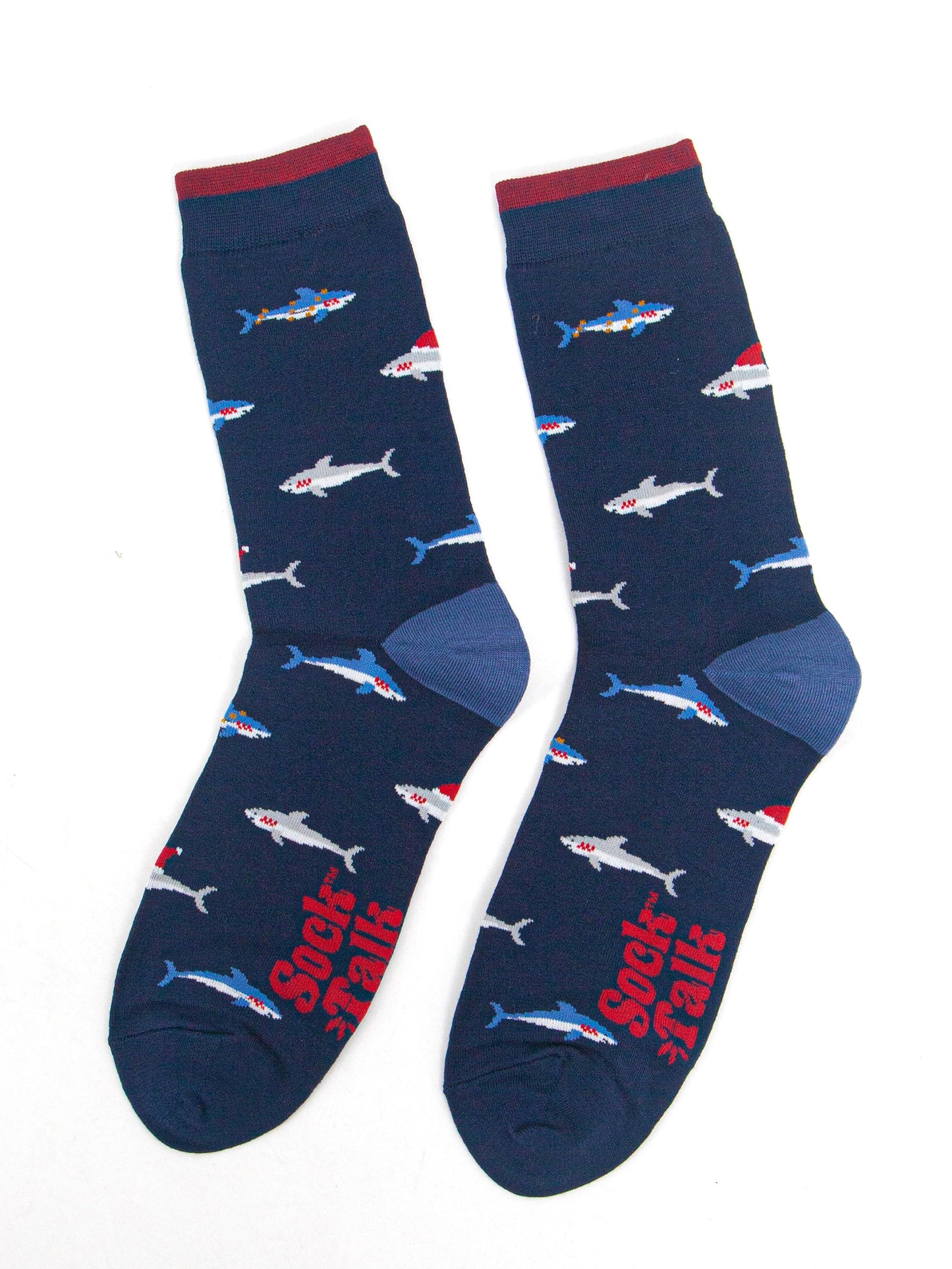 showing the shark socks laying flat, there is an all over pattern of swimming blue and grey sharks wearing festive hats and party lights