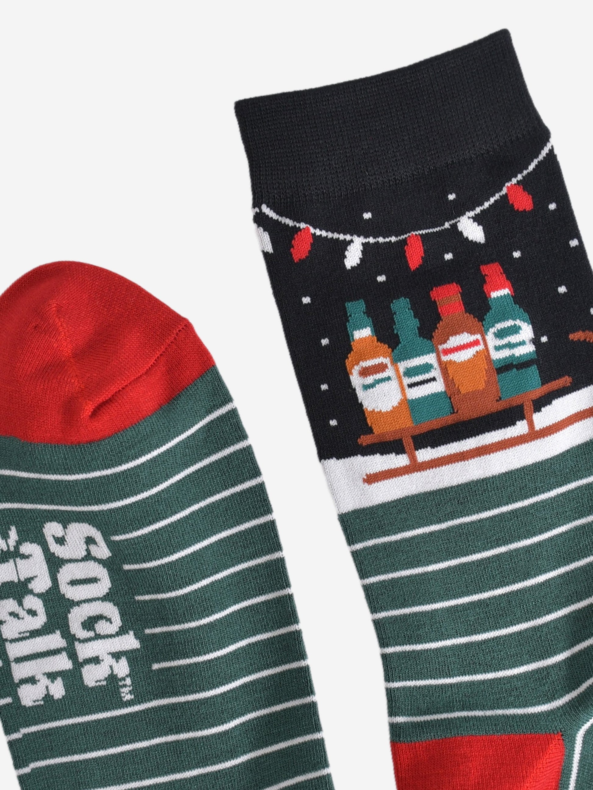 close up of the cuff and the toe of the socks, the toe is red in contrast to green of the socks, cuff is black in keeping with the winter night scene featuring the sledge and party lights