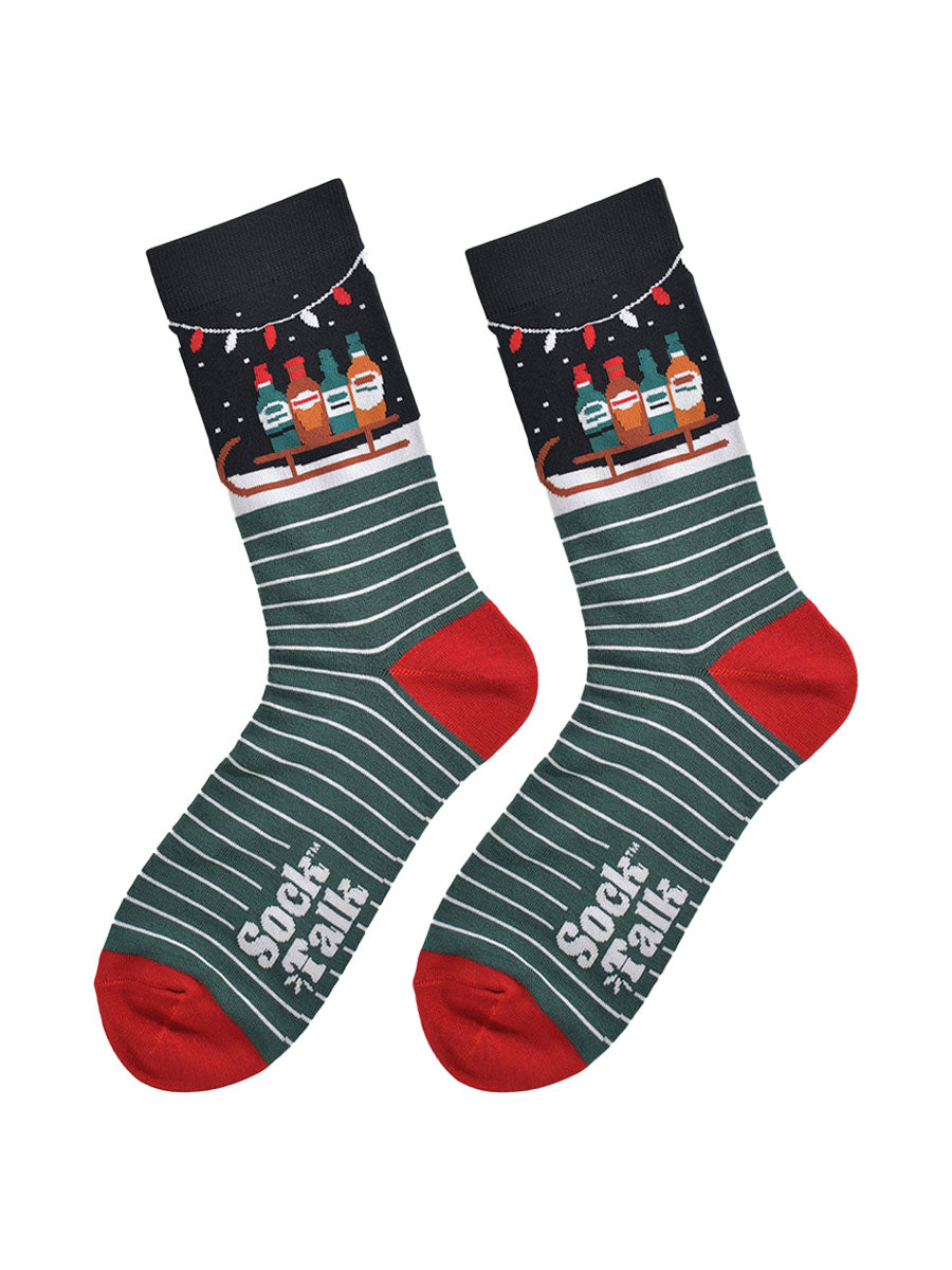 laying flat these socks show the green and white stripe pattern in contrast to the ankle which shows snow and a sledge carrying bottled party drinks