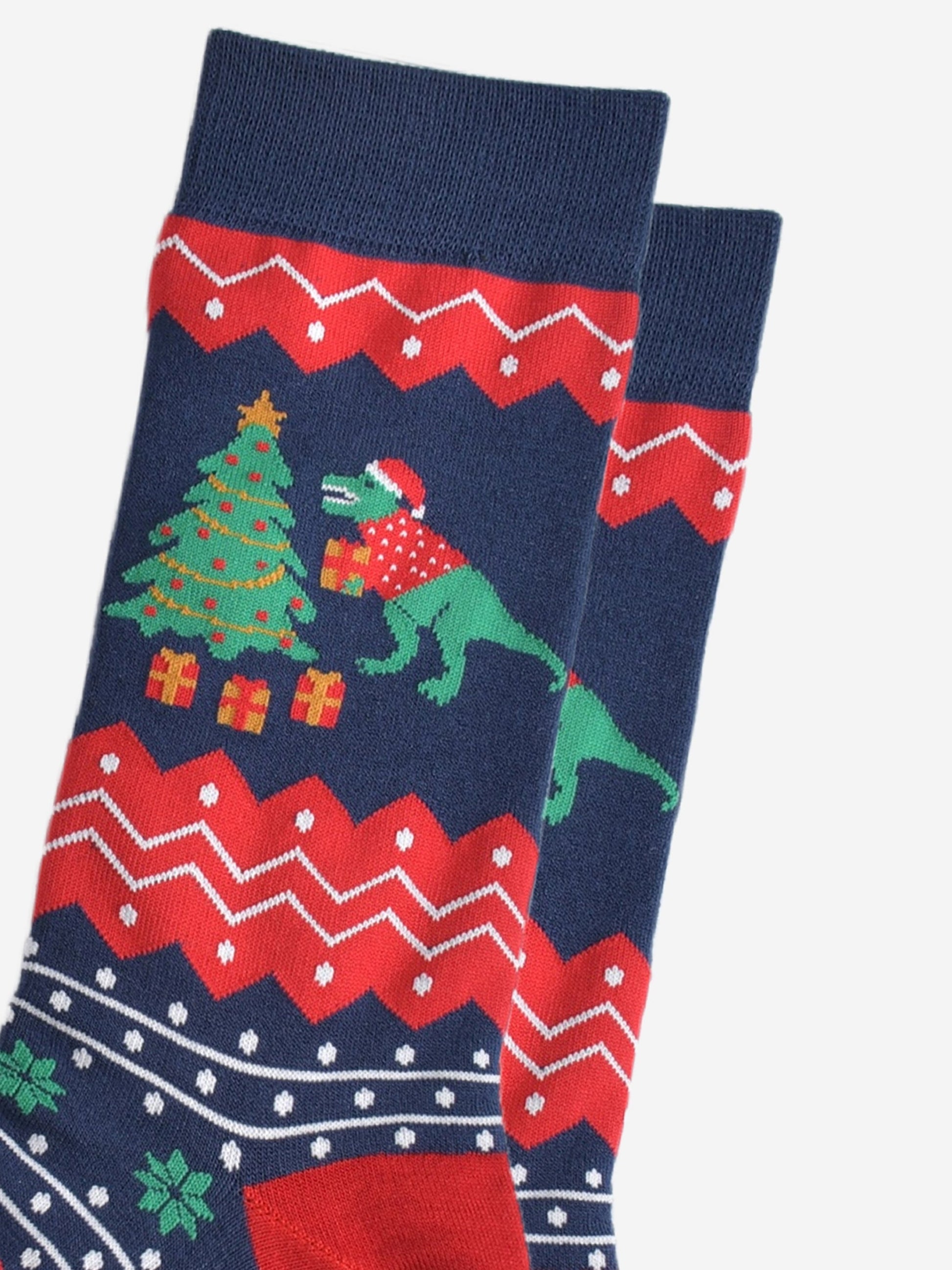 close up of the t-rex and xmas tree desing on the ankle, t-rex is putting gifts under the christmas tree and is holding one in his arms