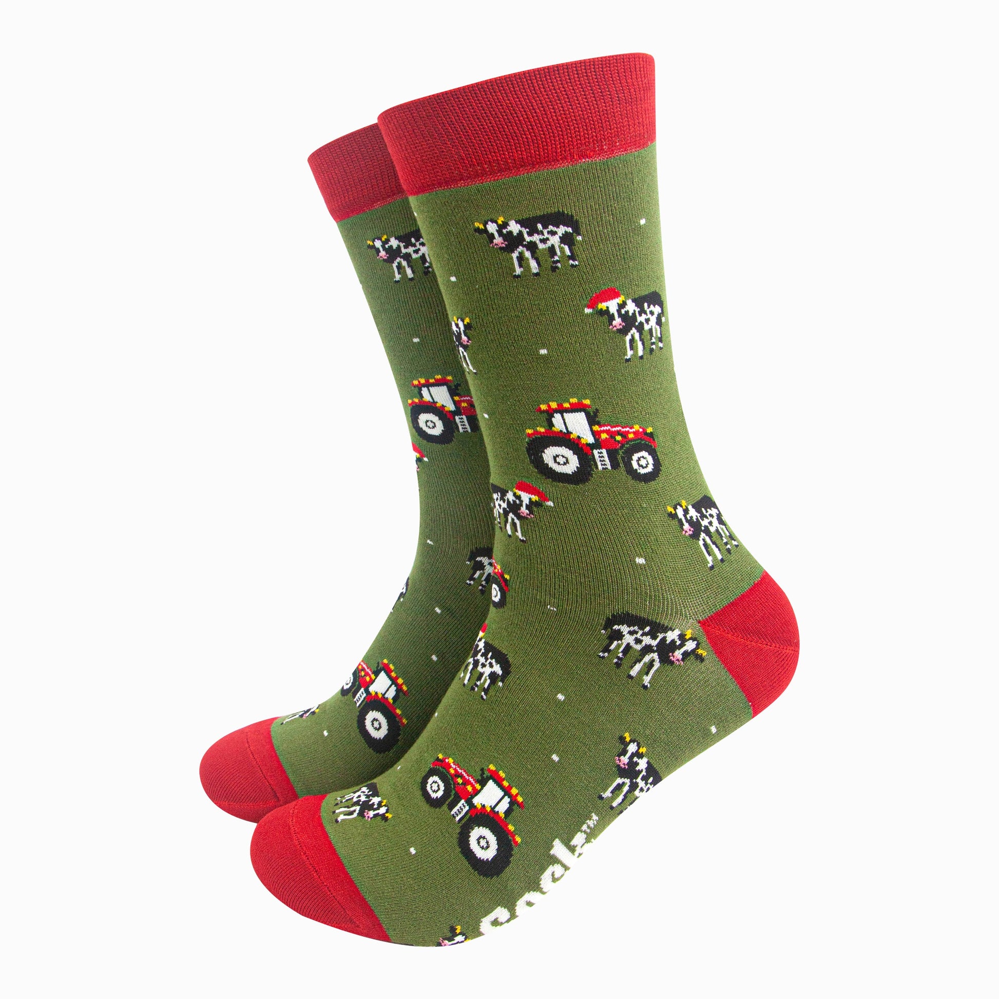 green socks with red accents and a pattern of red tractors and cows wearing santa hats