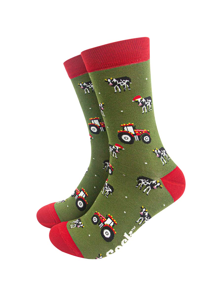 green socks with red accents and a pattern of red tractors and cows wearing santa hats