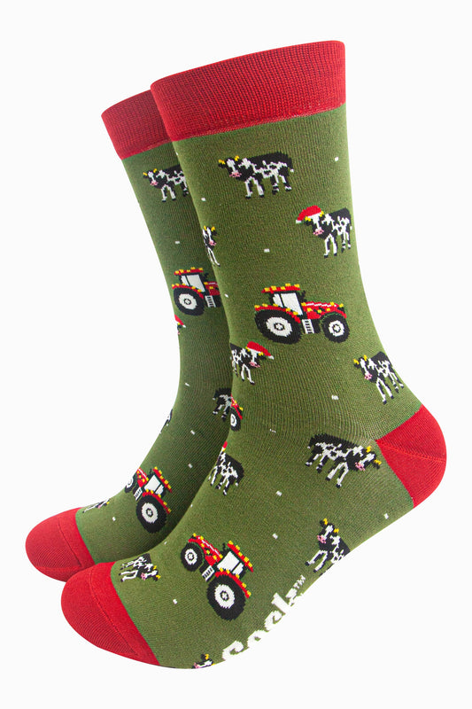 green socks with red accents and a pattern of red tractors and cows wearing santa hats