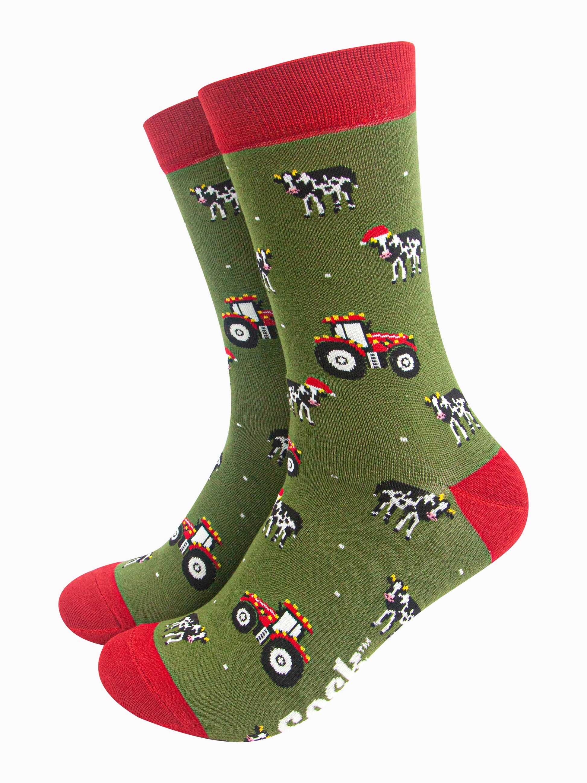 green socks with red accents and a pattern of red tractors and cows wearing santa hats