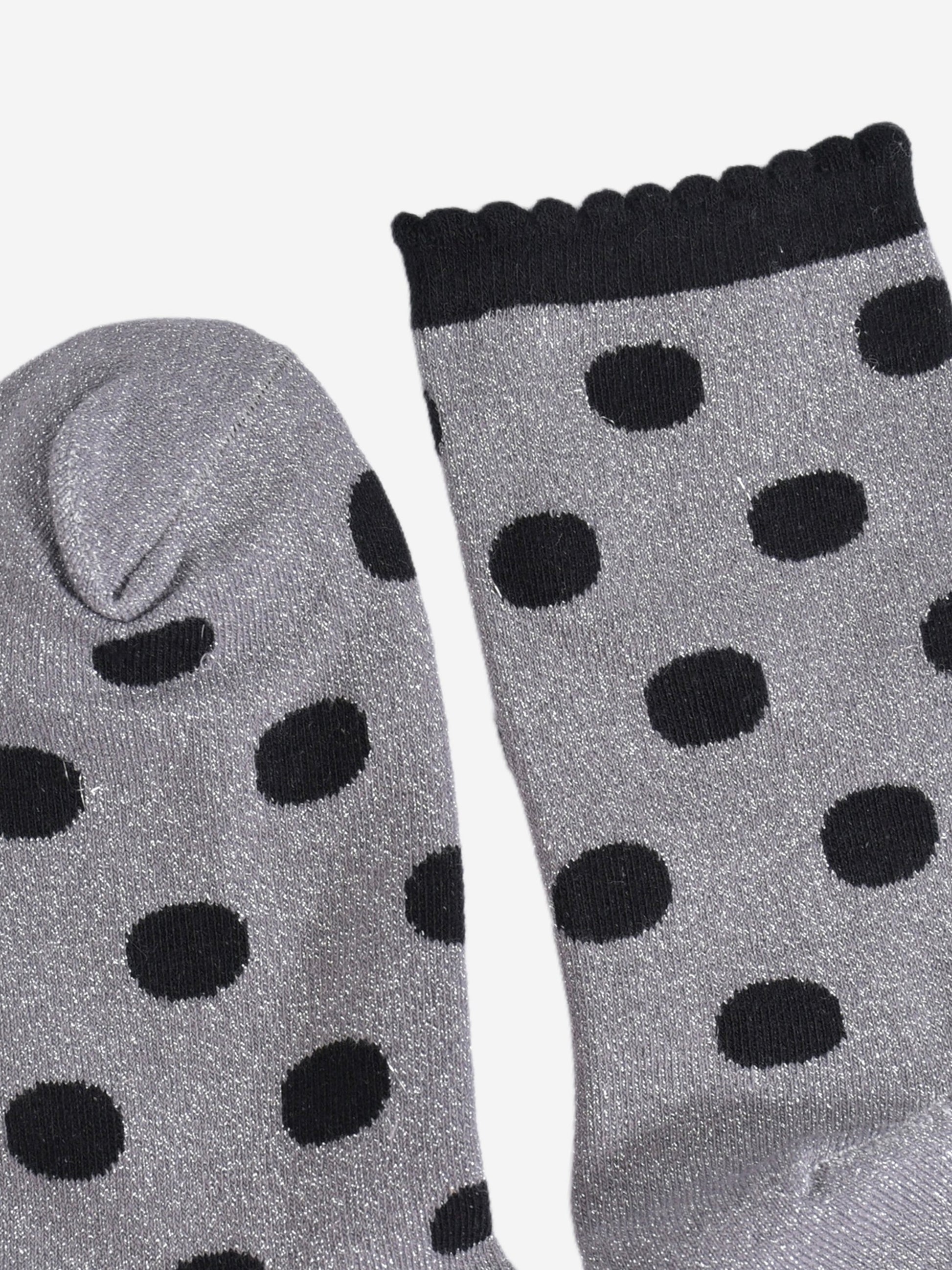 close up of the toe and cuff, the toe is grey with silver sparkles like the base of the socks, the cuff is black and has a scalloped edge