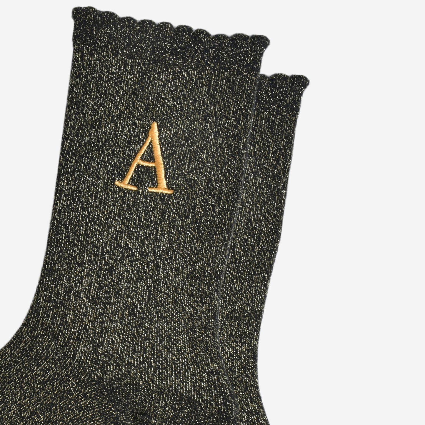 close up of the gold embroidered capital letter a on the ankle of the socks