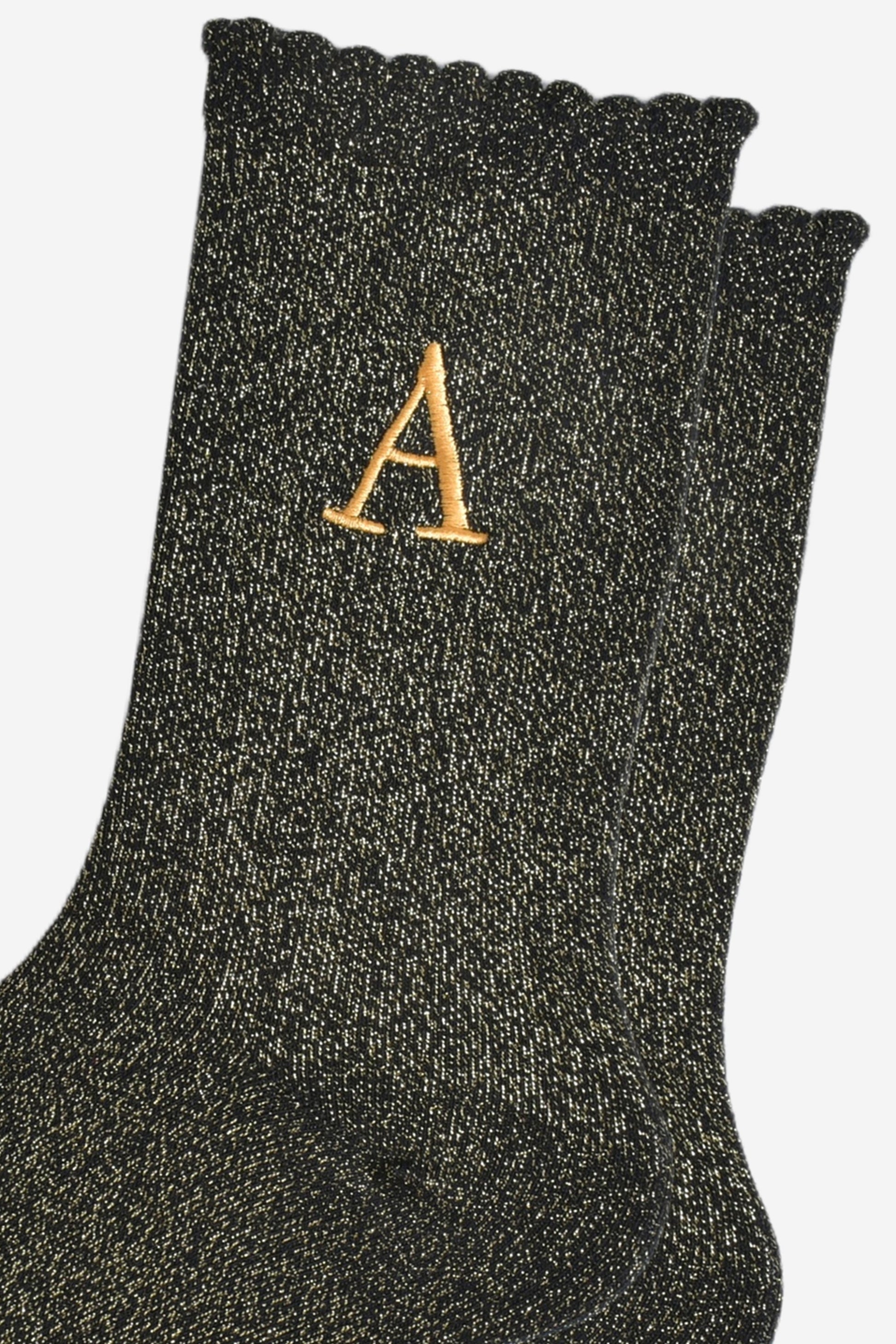 close up of the gold embroidered capital letter a on the ankle of the socks