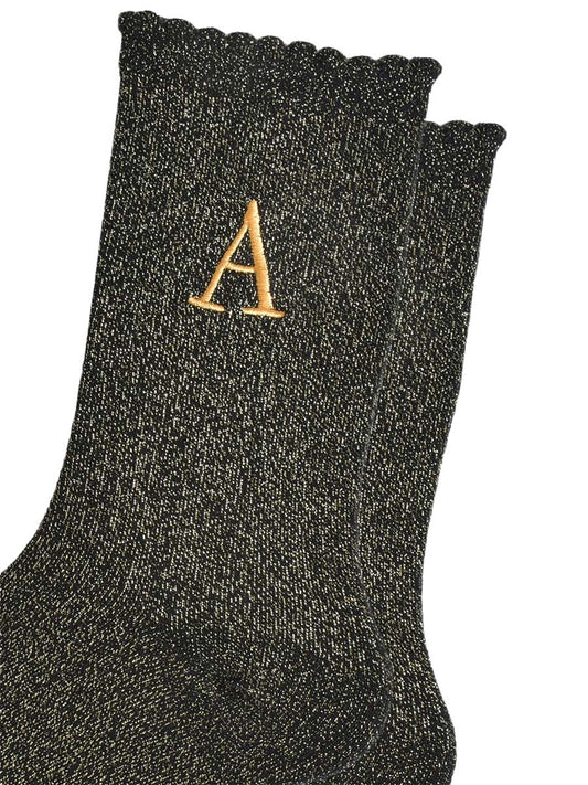 close up of the gold embroidered capital letter a on the ankle of the socks