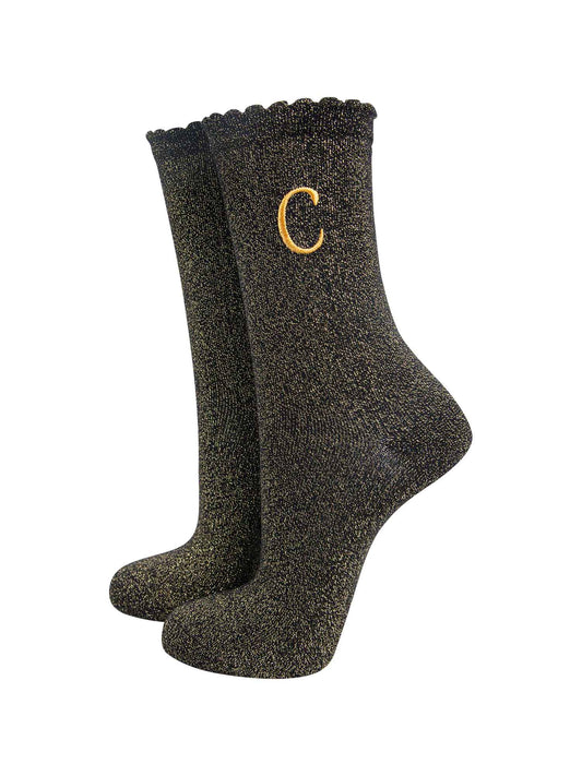 black ankle socks with a scalloped cuff, with an all over gold glitter sparkle and an embroidered gold letter c on the ankle