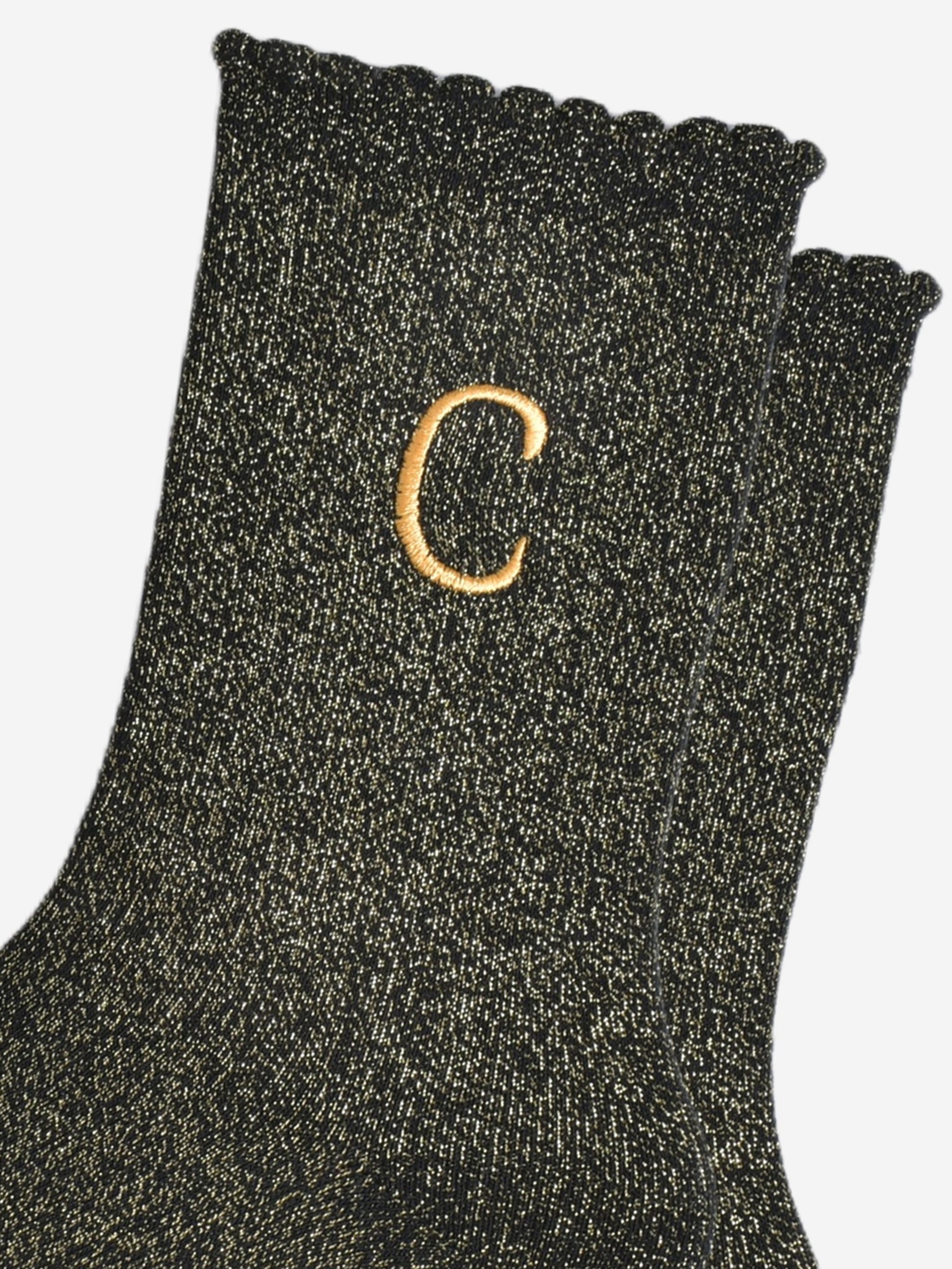 close up of the gold embroidered capital letter c on the ankle of the socks
