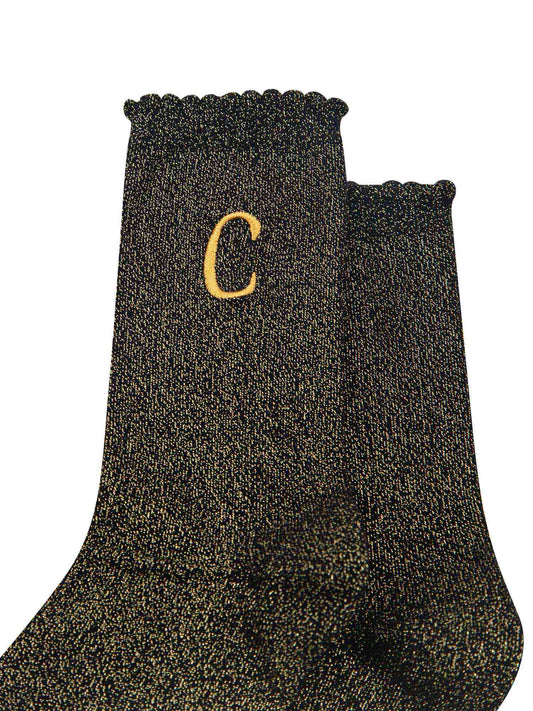 close up of the gold embroidered capital letter c on the ankle of the socks