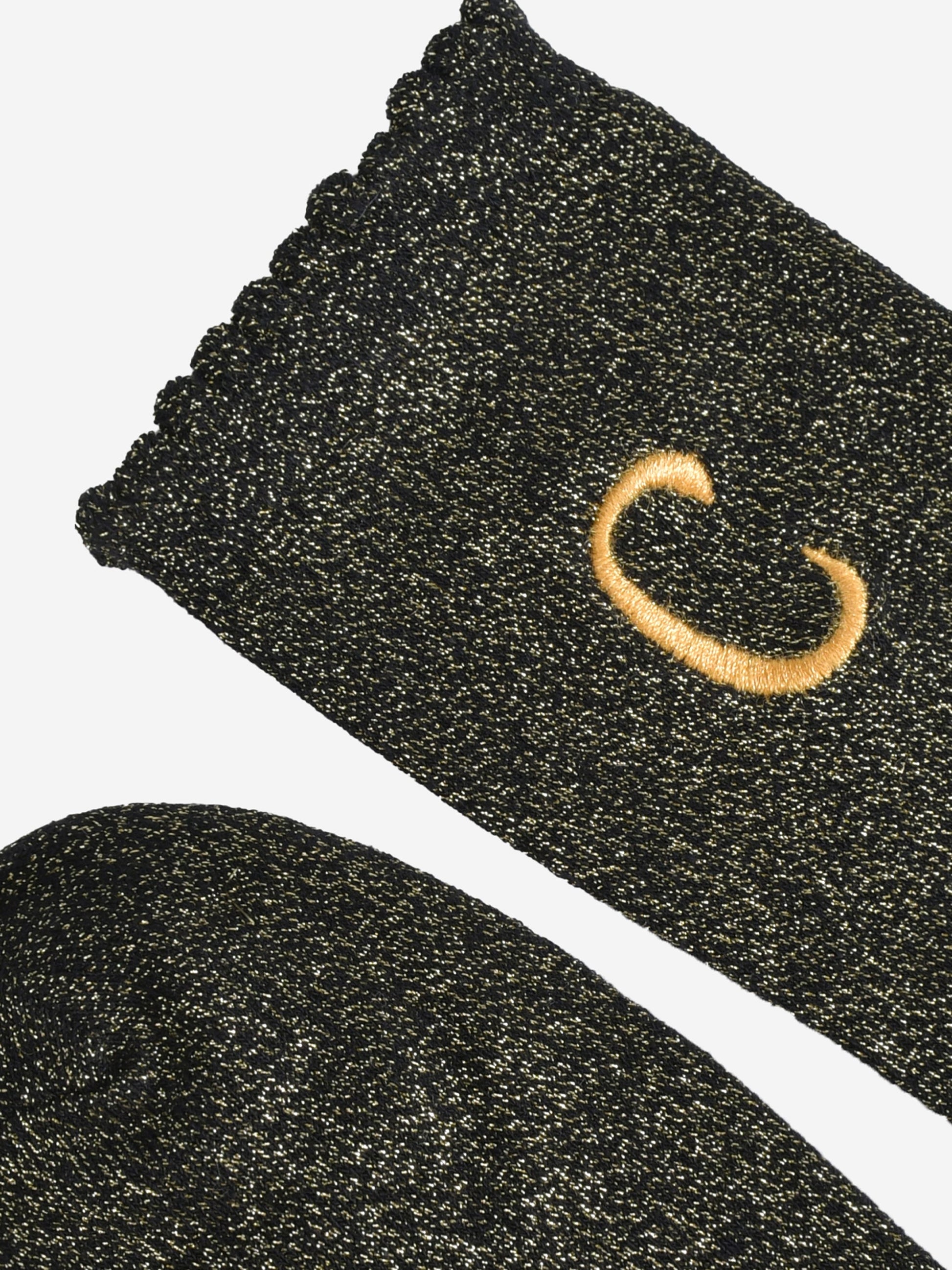 close up of the scalloped cuff on the socks, the toe is the same black and gold as the rest of the socks