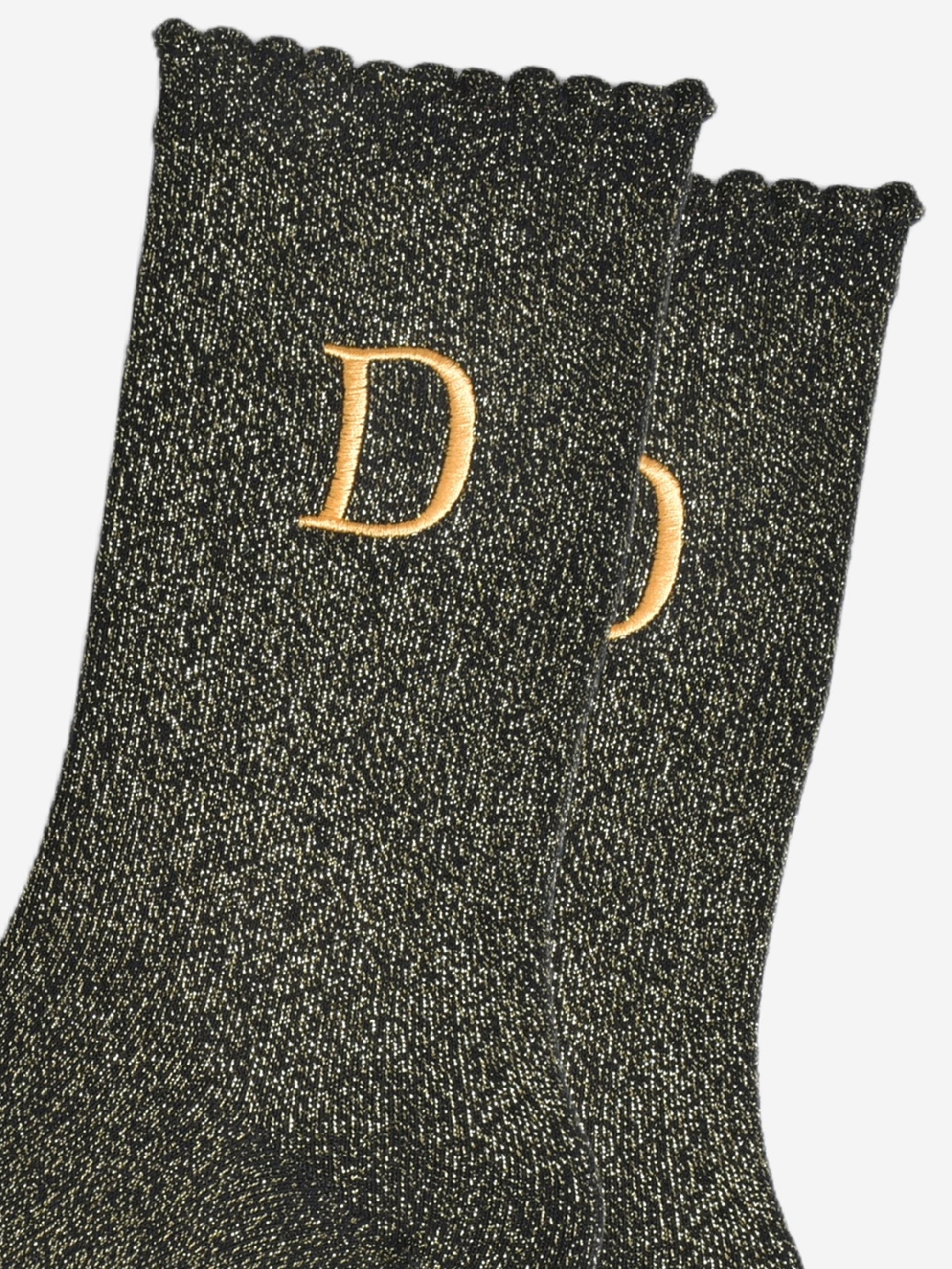 close up of the gold embroidered capital letter d on the ankle of the socks